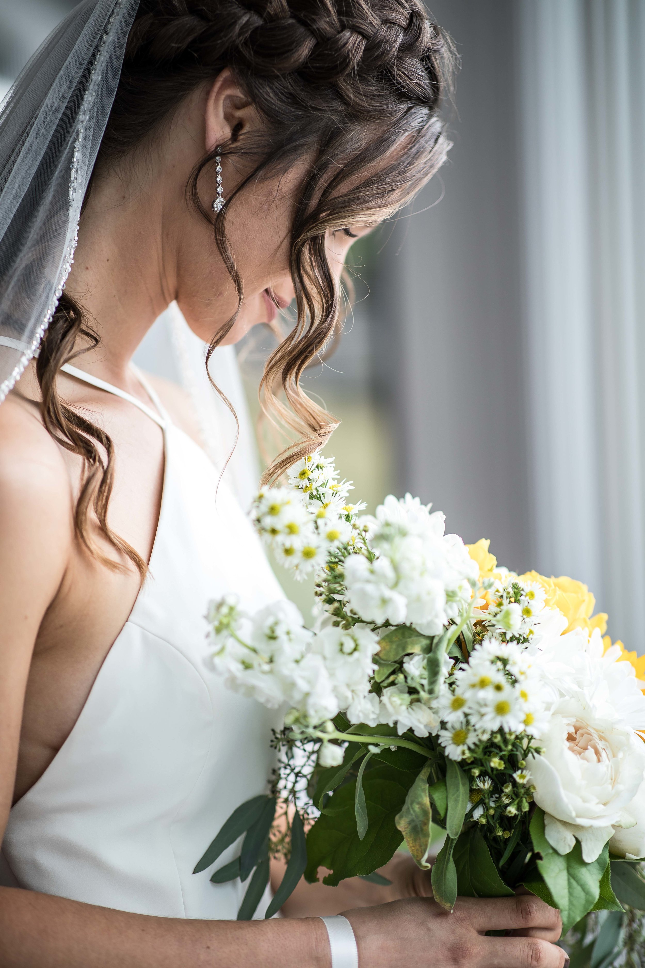  bride looks down into her flower bouquet  