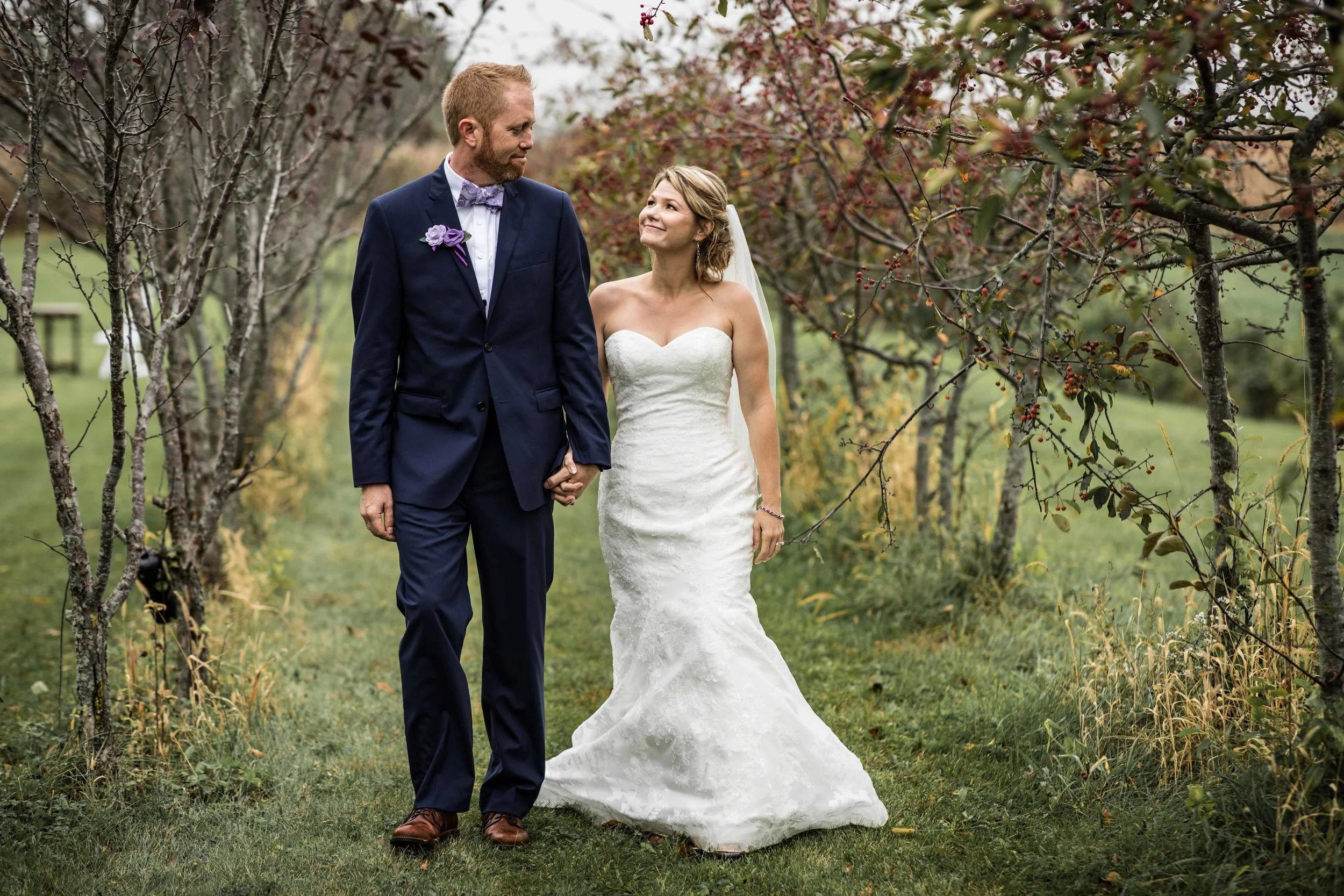 bride and groom walking through a row of trees