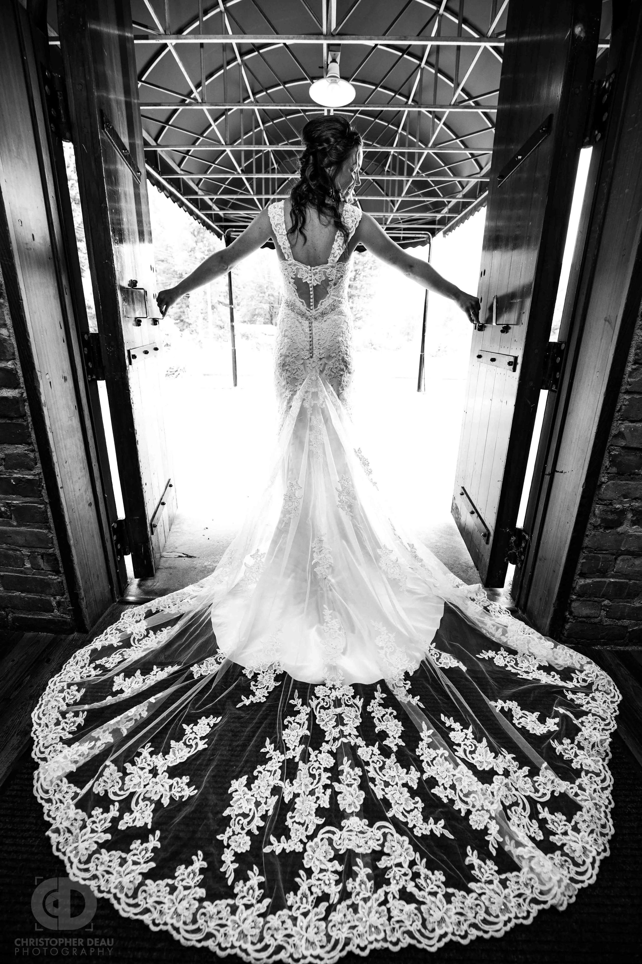 Stunning bride in flowing white lace dress standing in door way