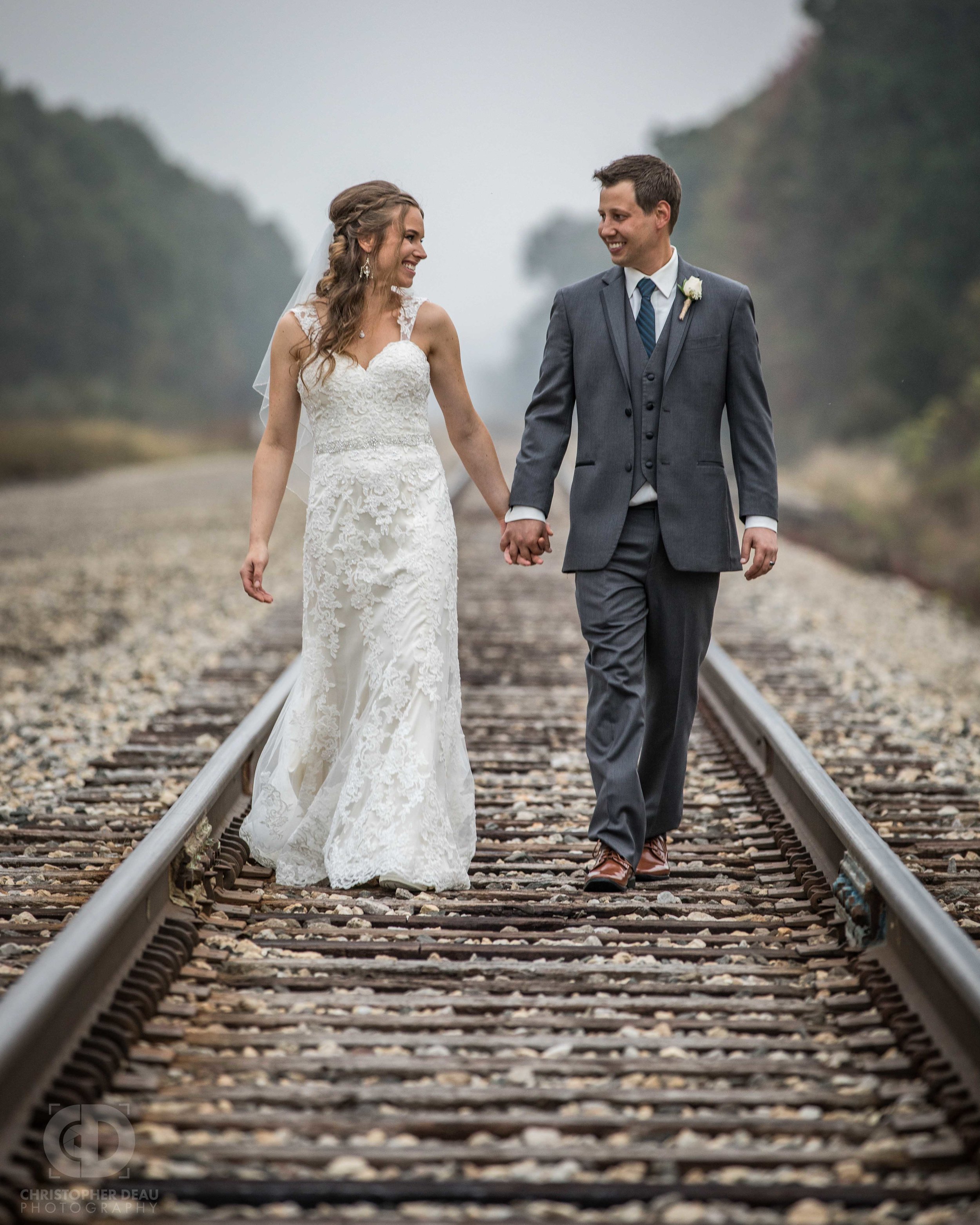  bride and groom walking down railroad tracks 