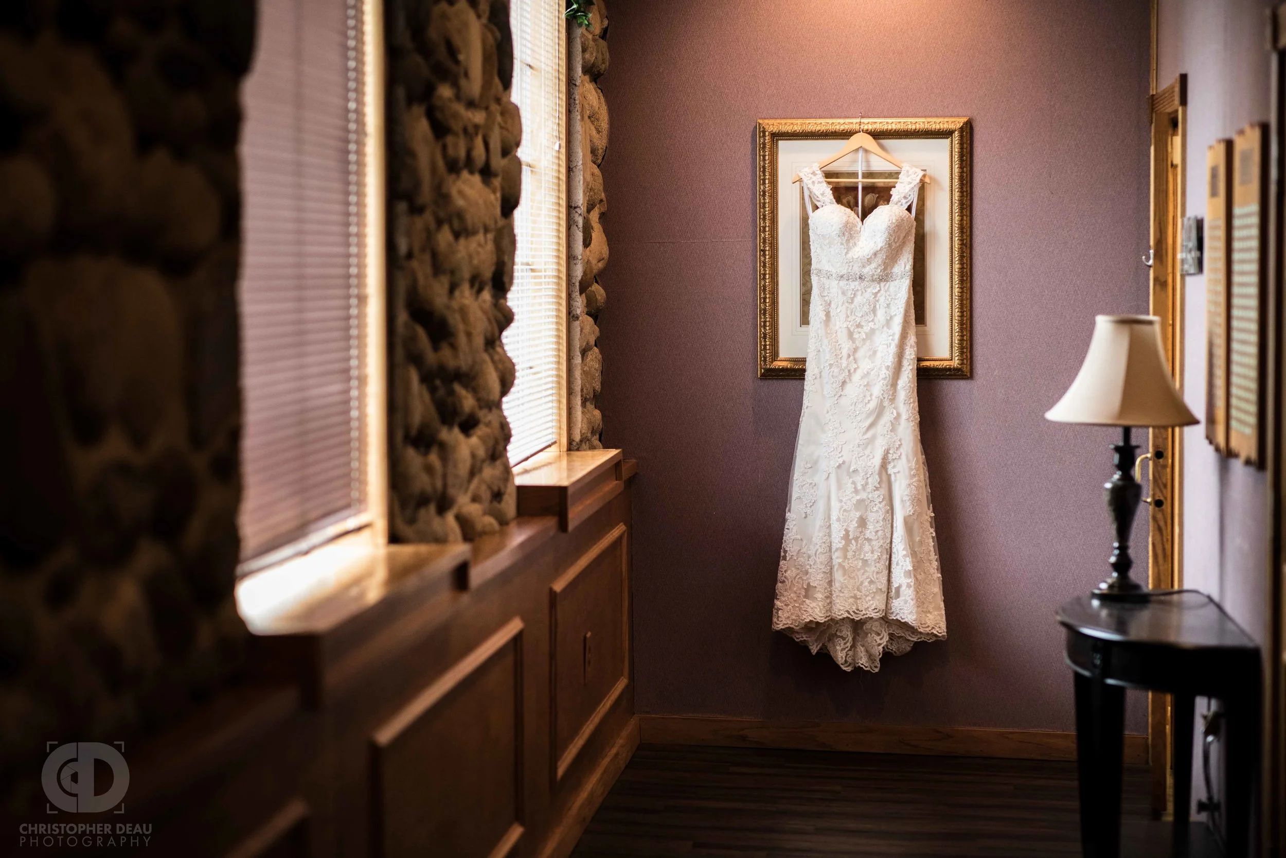 The brides white dress hanging at the end of a hallway