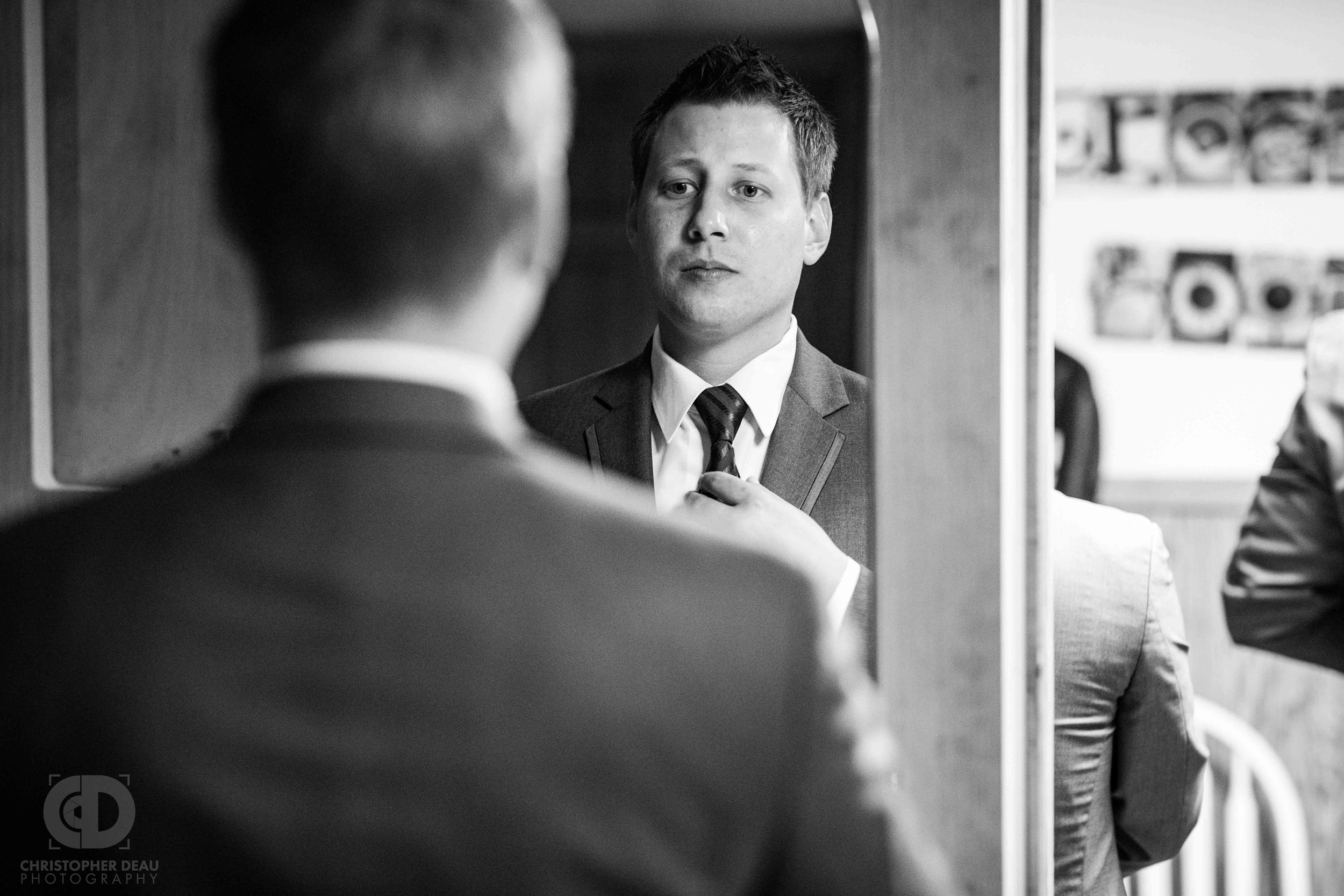  Groom straightening tie in the mirror 