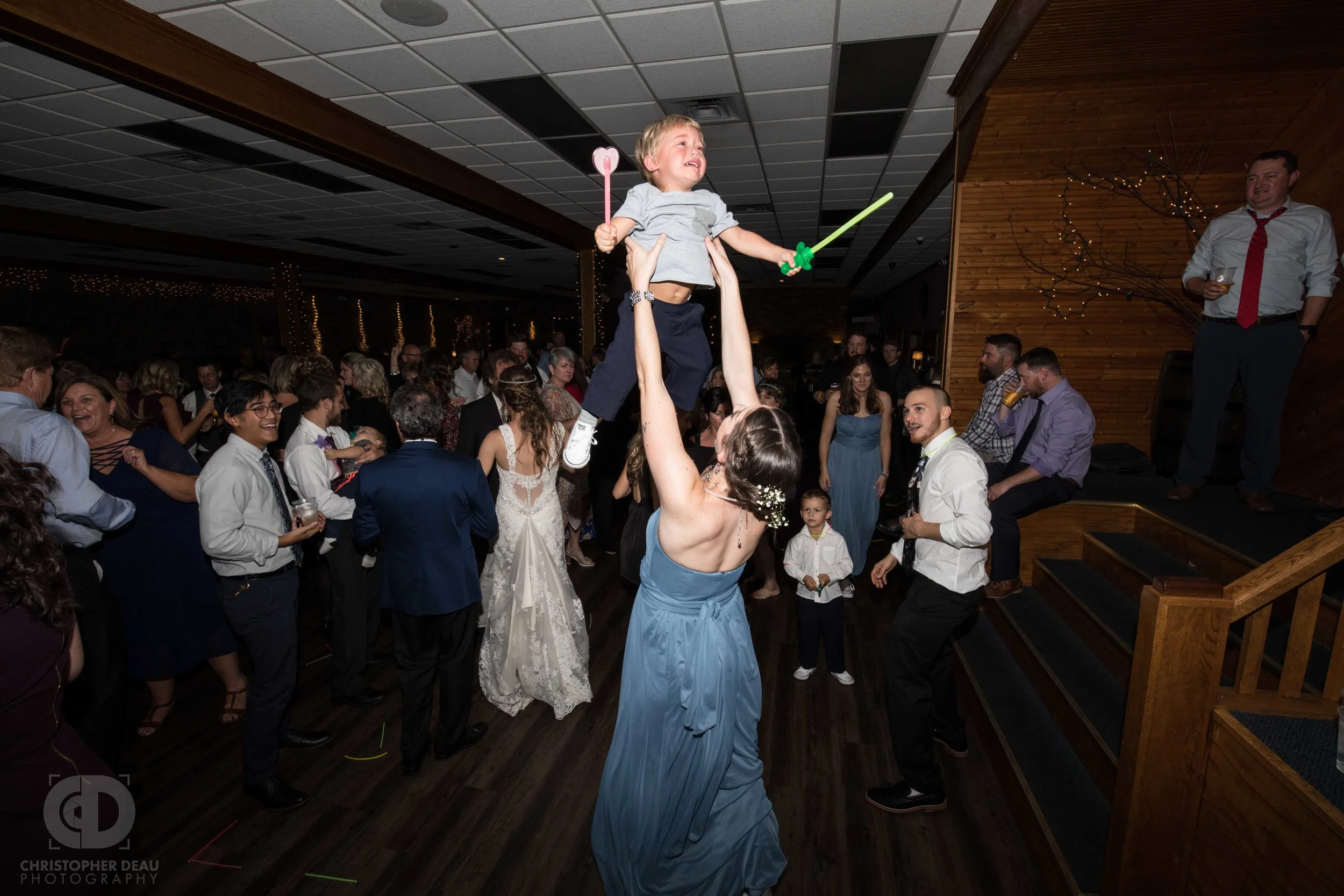 Bridesmaid throwing crying toddler into the air on the dance floor