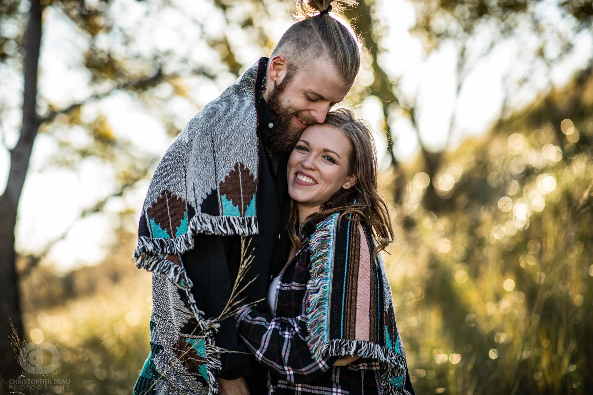 an engaged couple wrapped in a blanket surrounded by lake Michigan dune grass