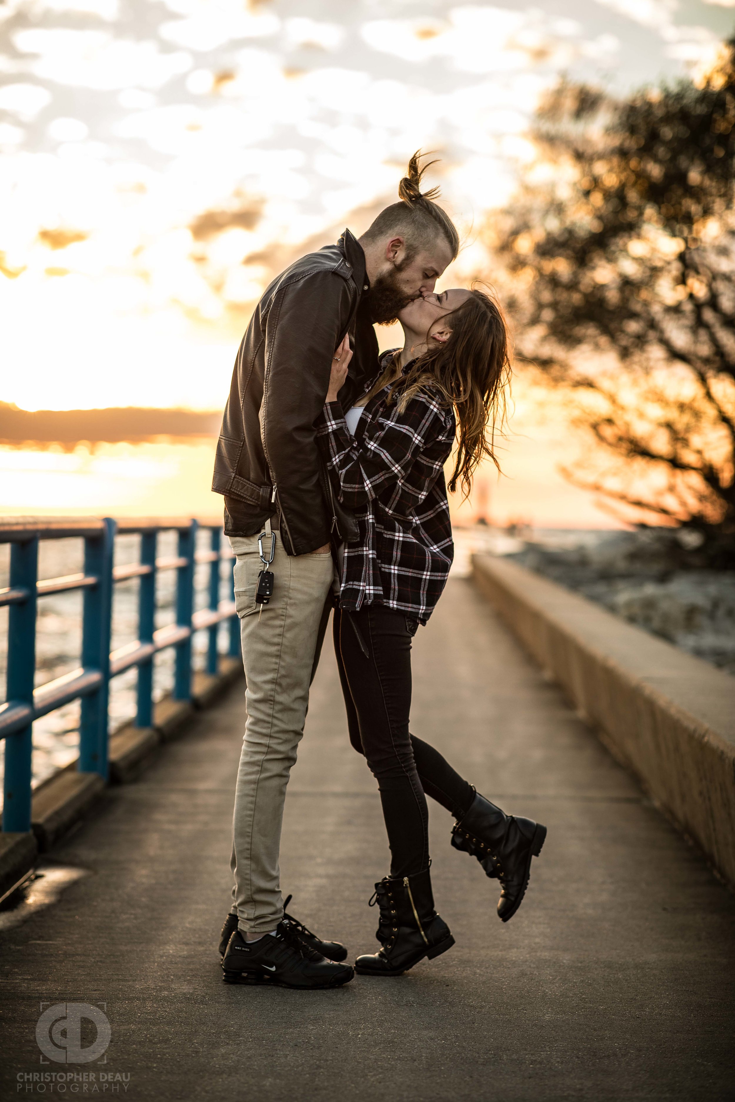  a couple leans in for a kiss on a long pier in Northern Michigan 