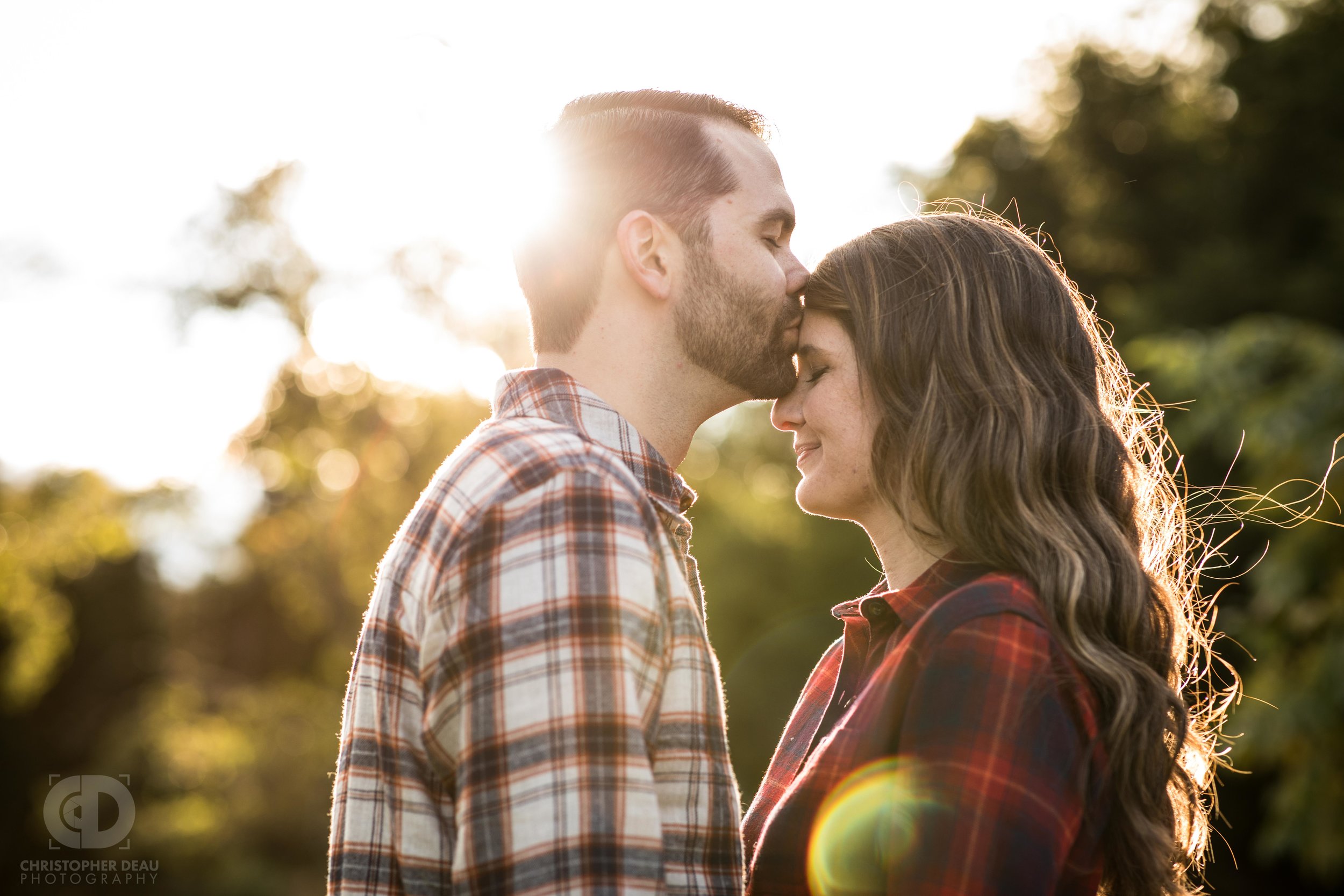  he kisses her head with the sunlight glaring behind 