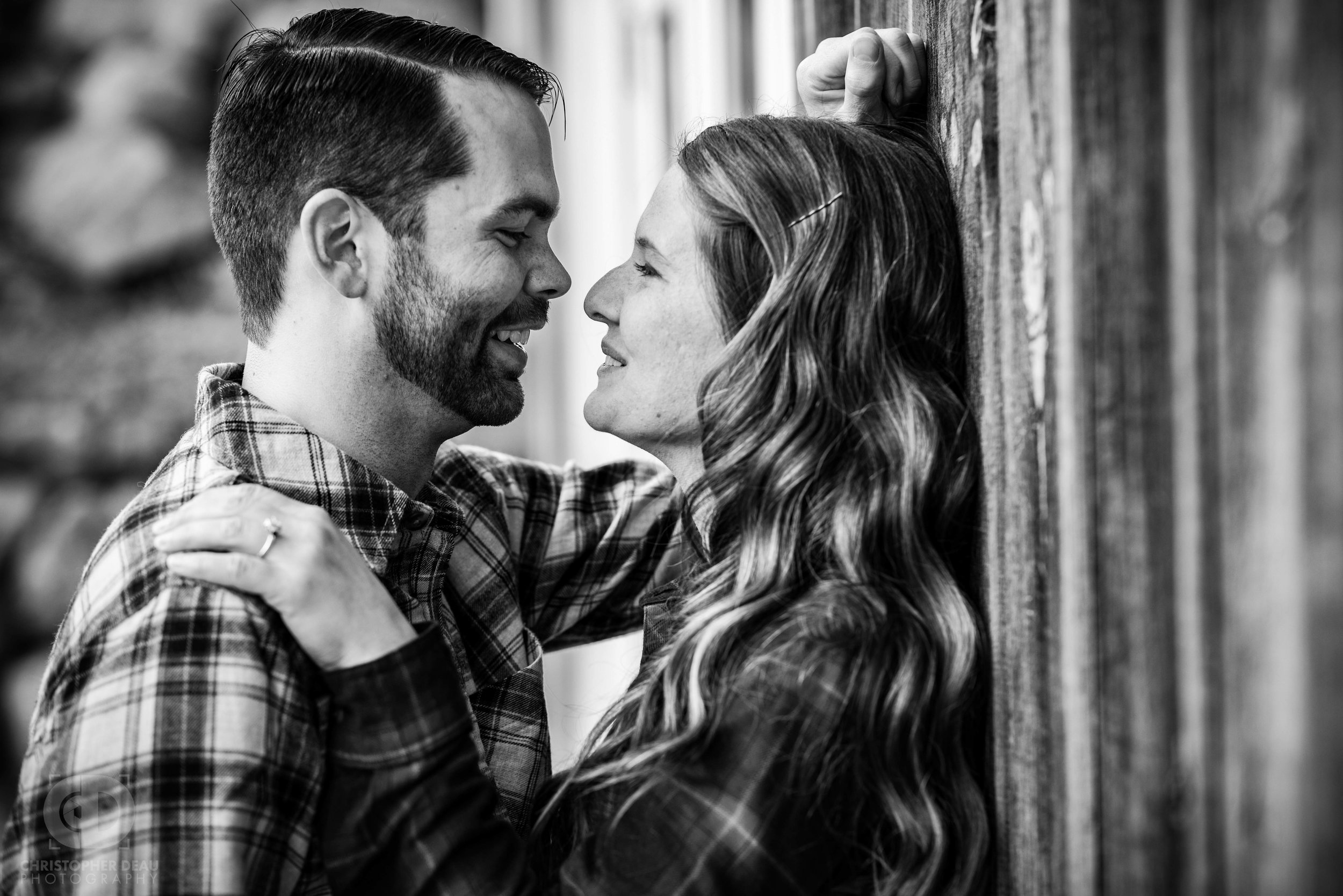  black and white image of engagement photos with man and woman against a rustic wood barn in Southwest Michigan 