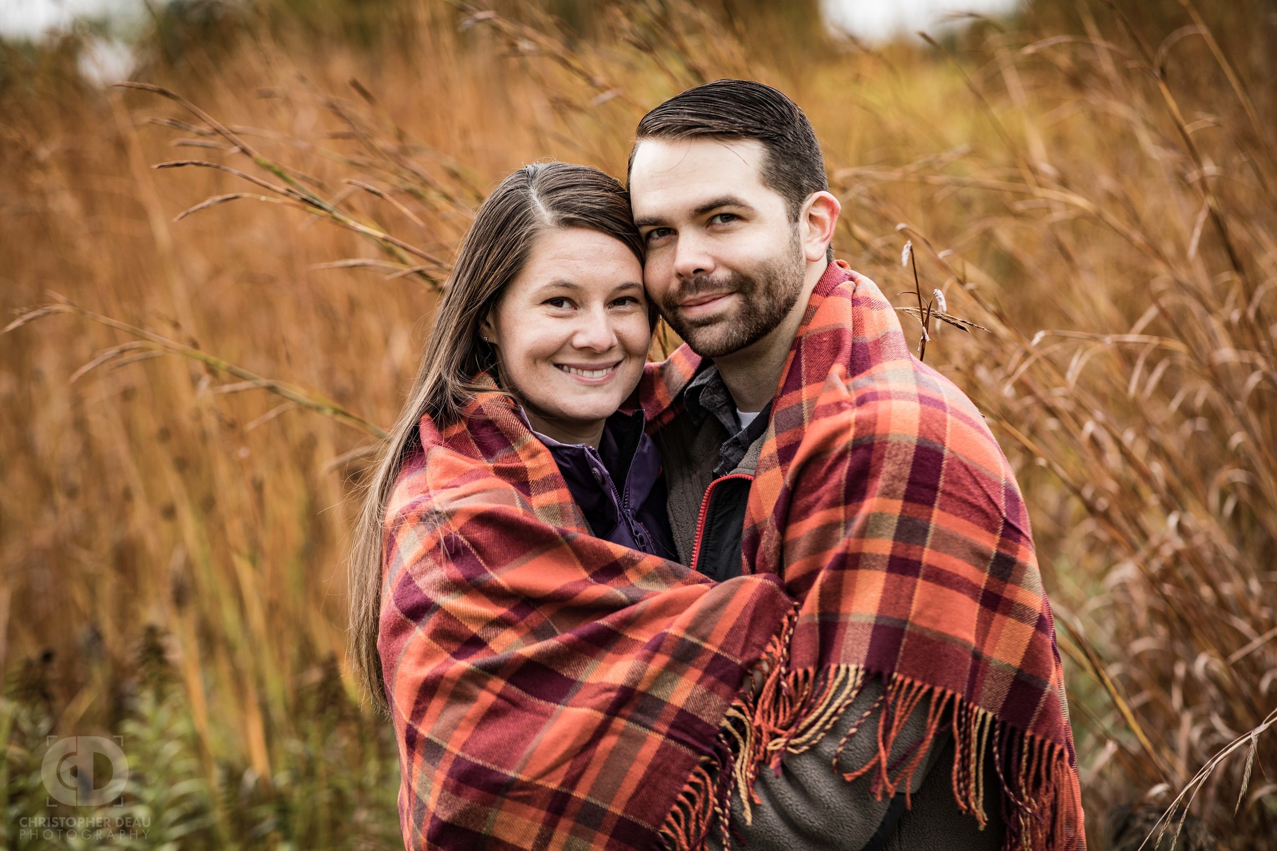  couple wrapped in blanket during cold fall day in a tall grass prairie in southwest Michigan 
