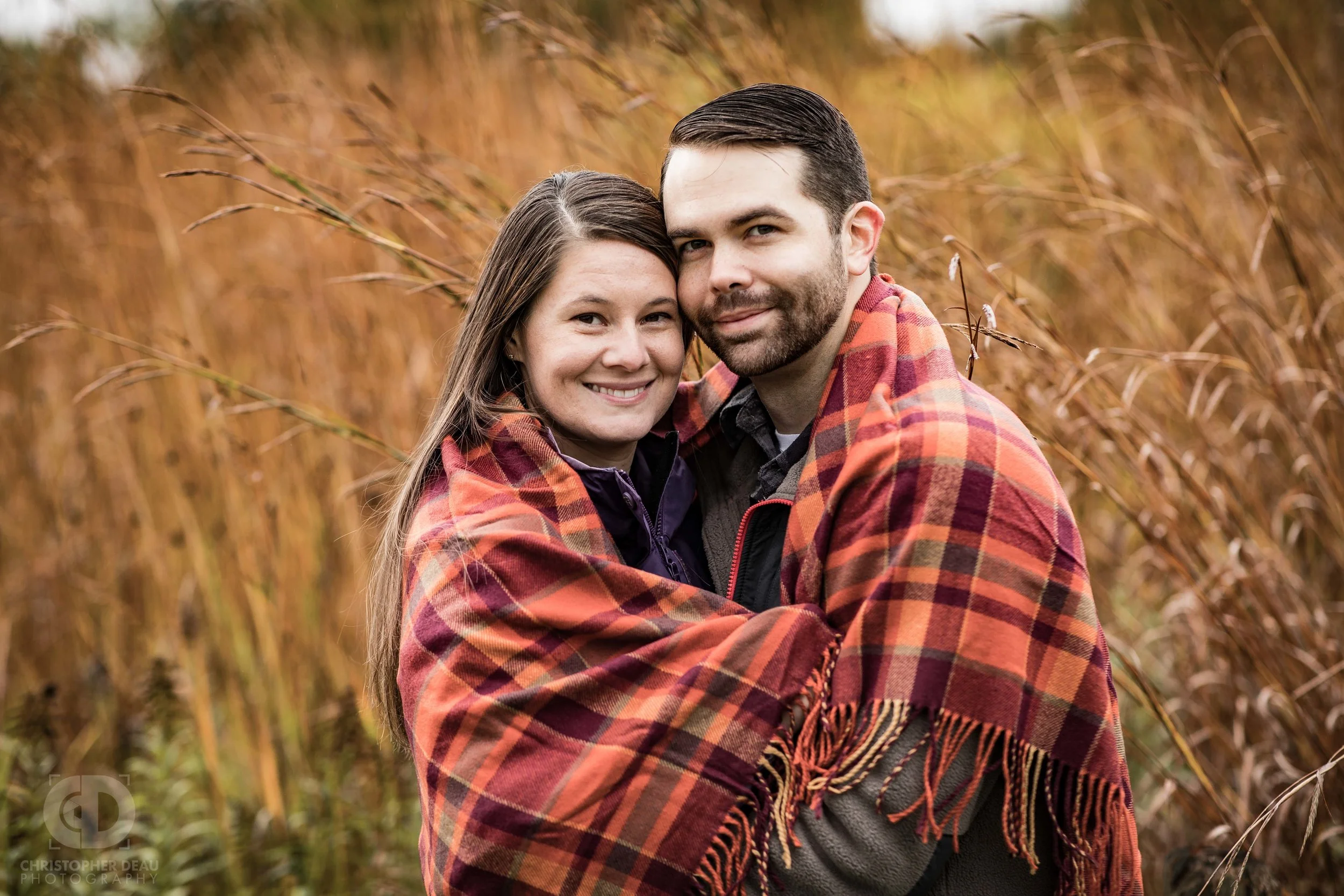 couple wrapped in blanket during cold fall day in a tall grass prairie in southwest Michigan