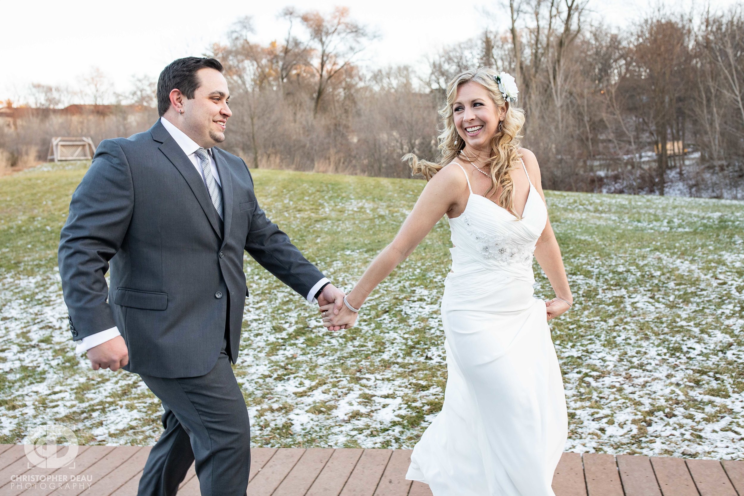  bride running with groom on the grounds of the Girl Scouts Heart of Michigan reception hall 