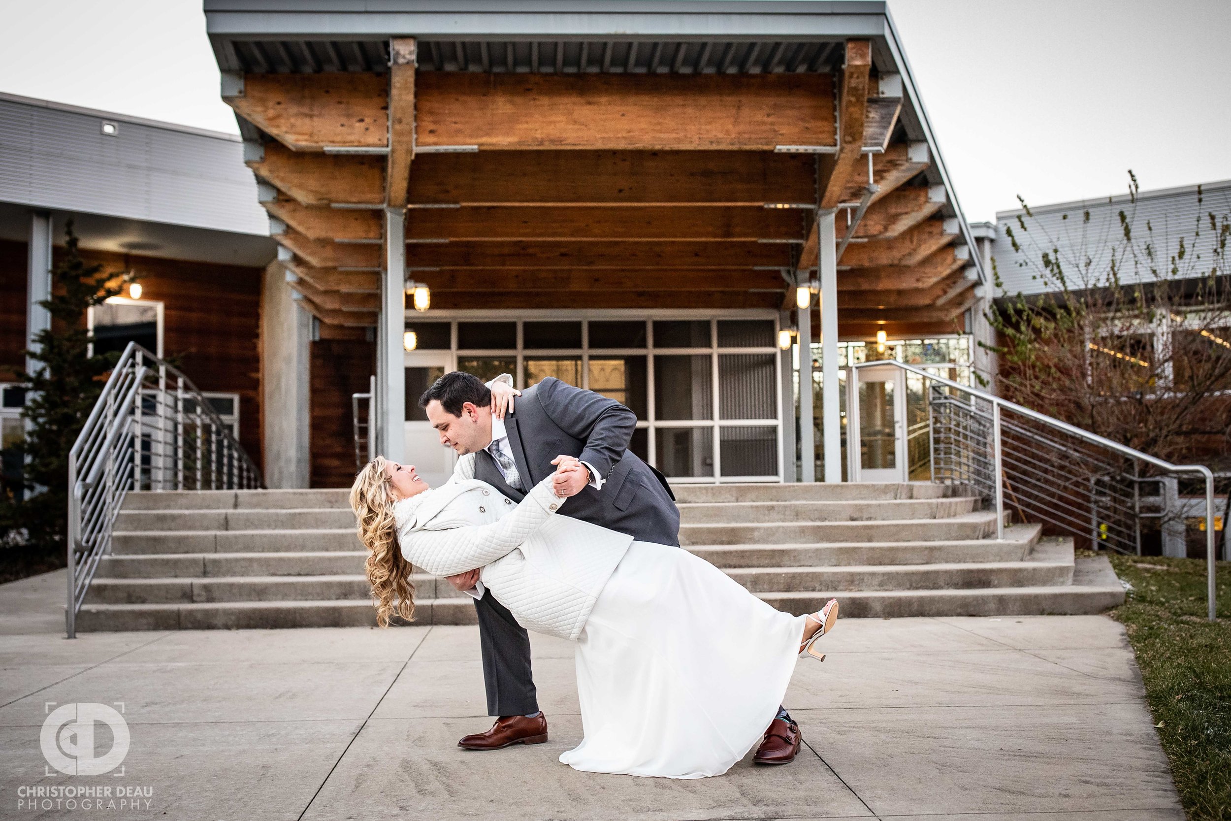  The Groom dips and kisses his bride in front of the Girl Scouts Heart of Michigan Building in Kalamazoo during their wedding reception 