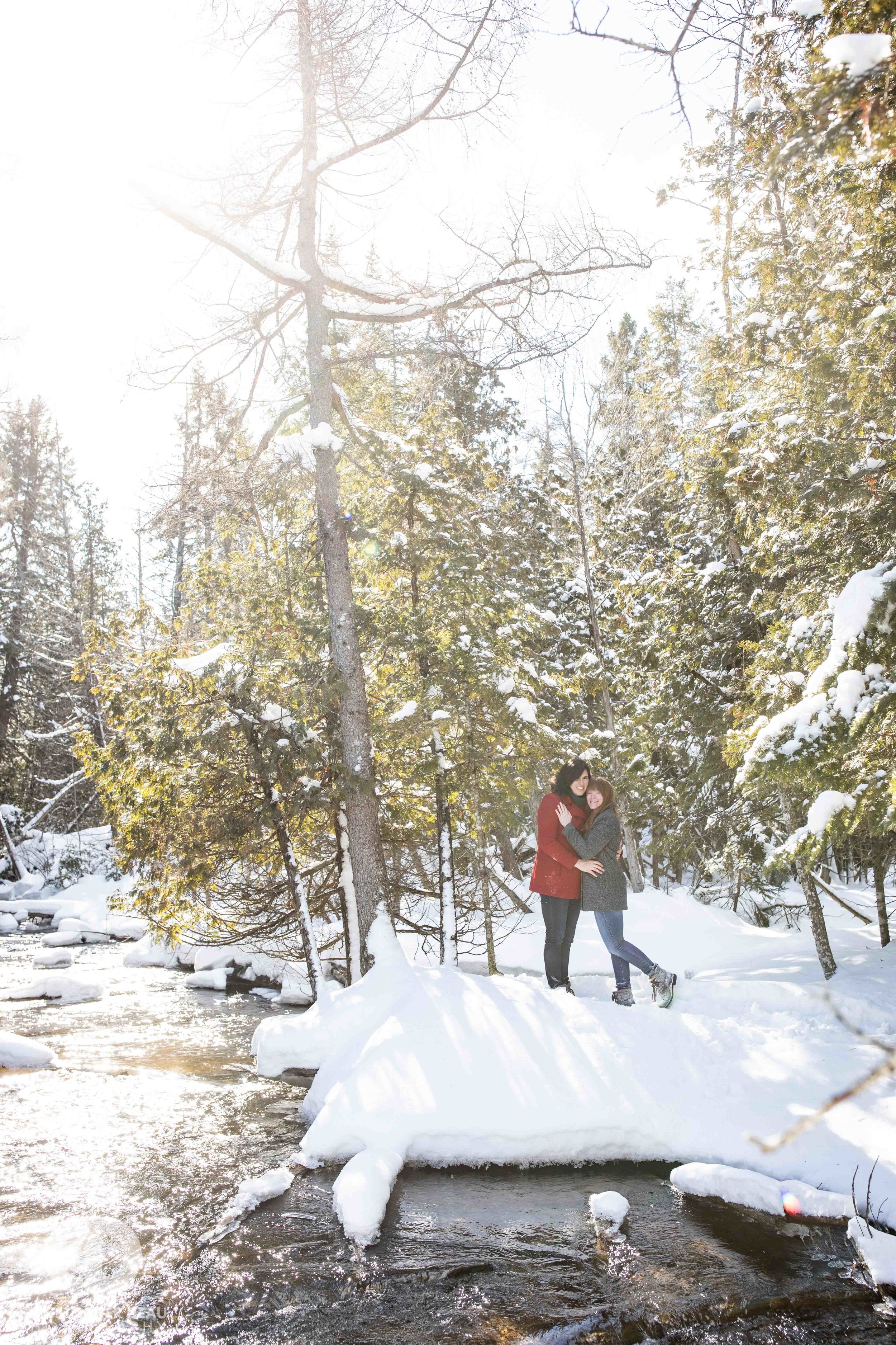  Snow covered pines and stream in Northern Michigan Woods during engagement photos 