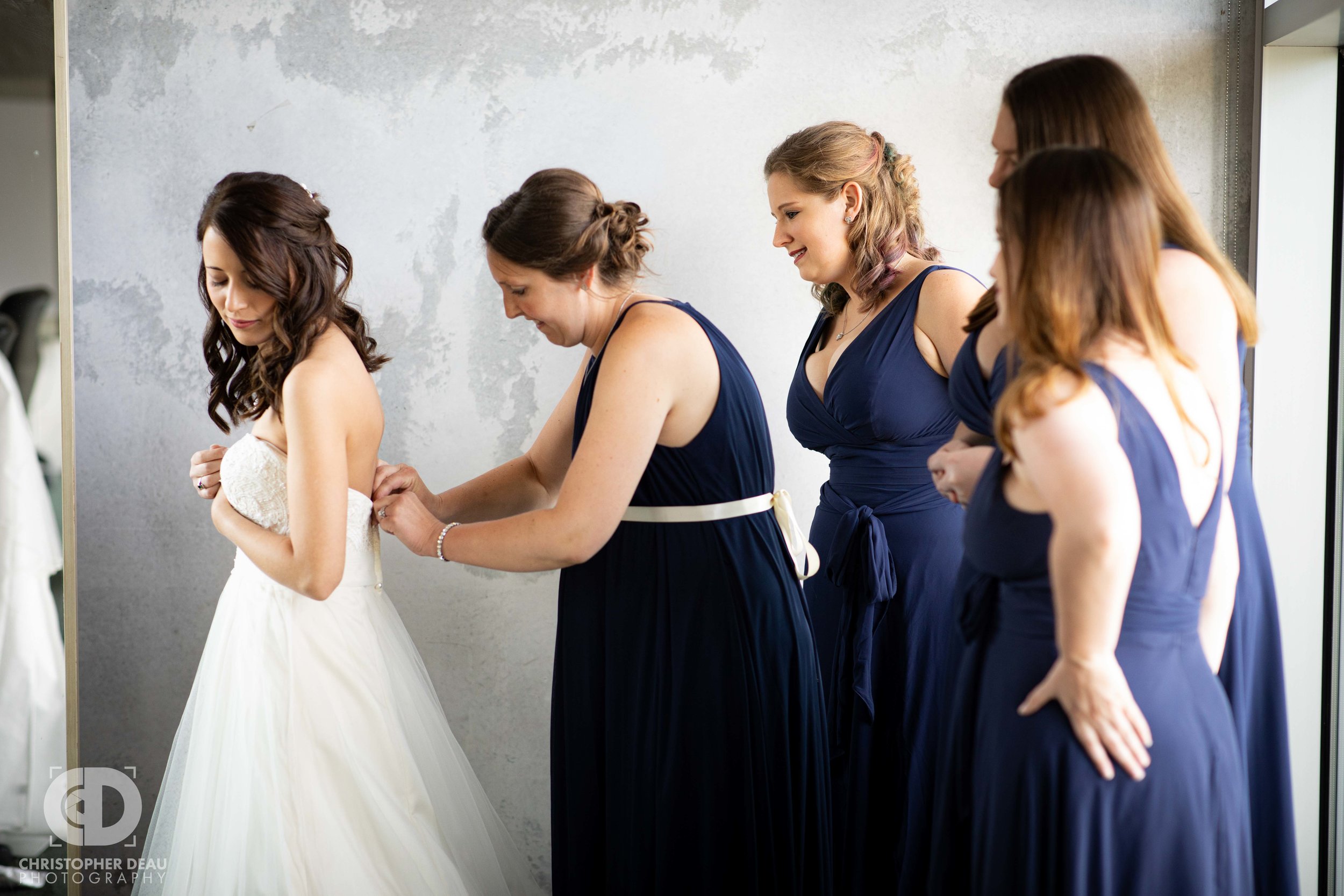  bridal party getting the bride into her dress 