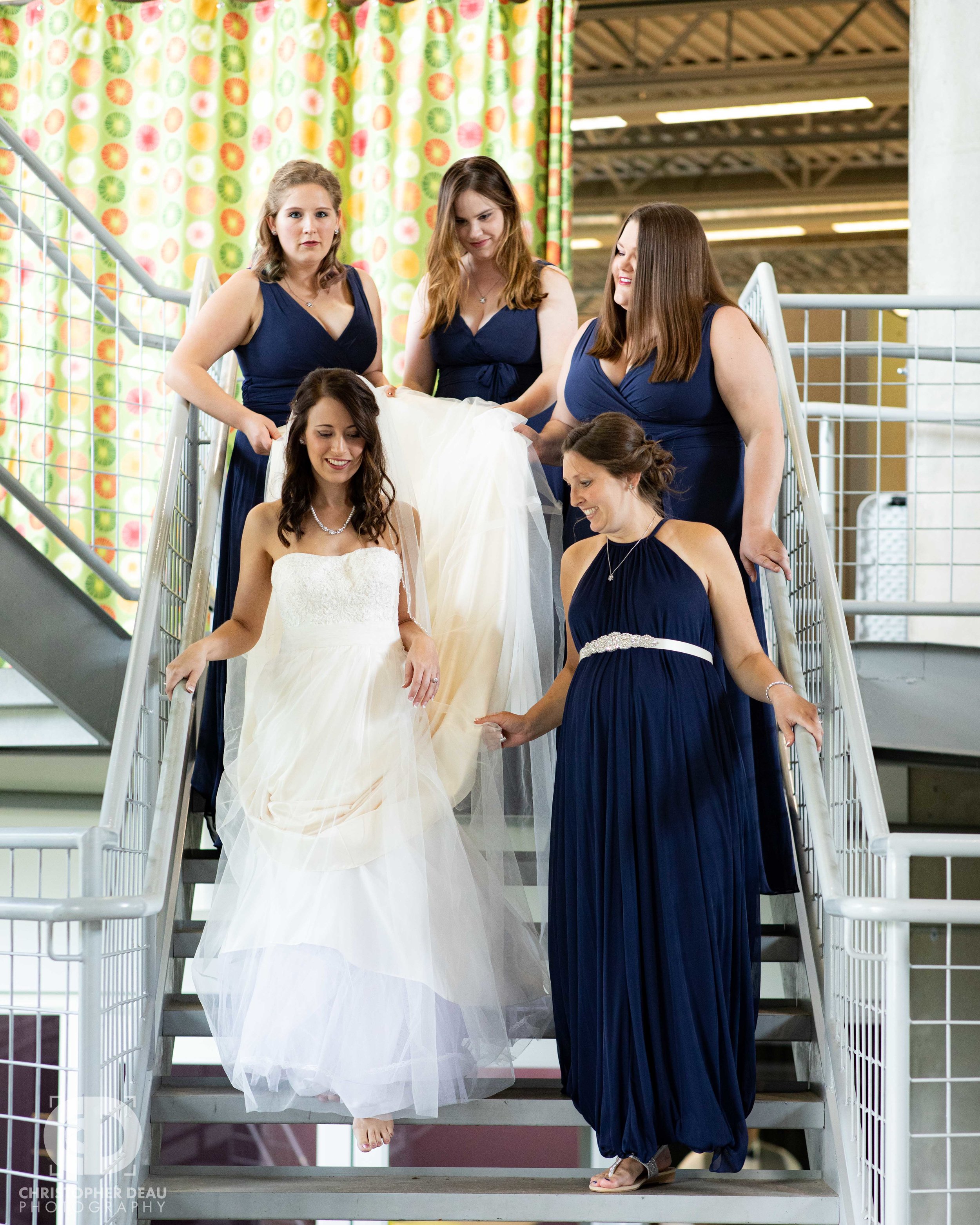  bridesmaids helping bride down the stairs  