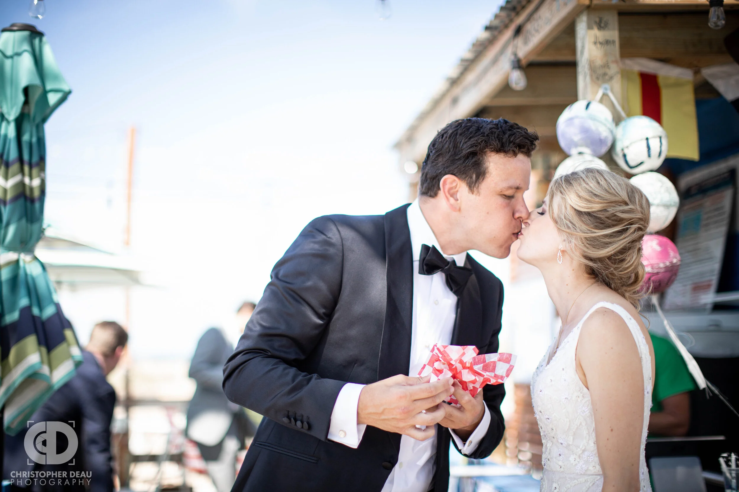 bride and groom find a hotdog stand at the beach and stop for a quick snack