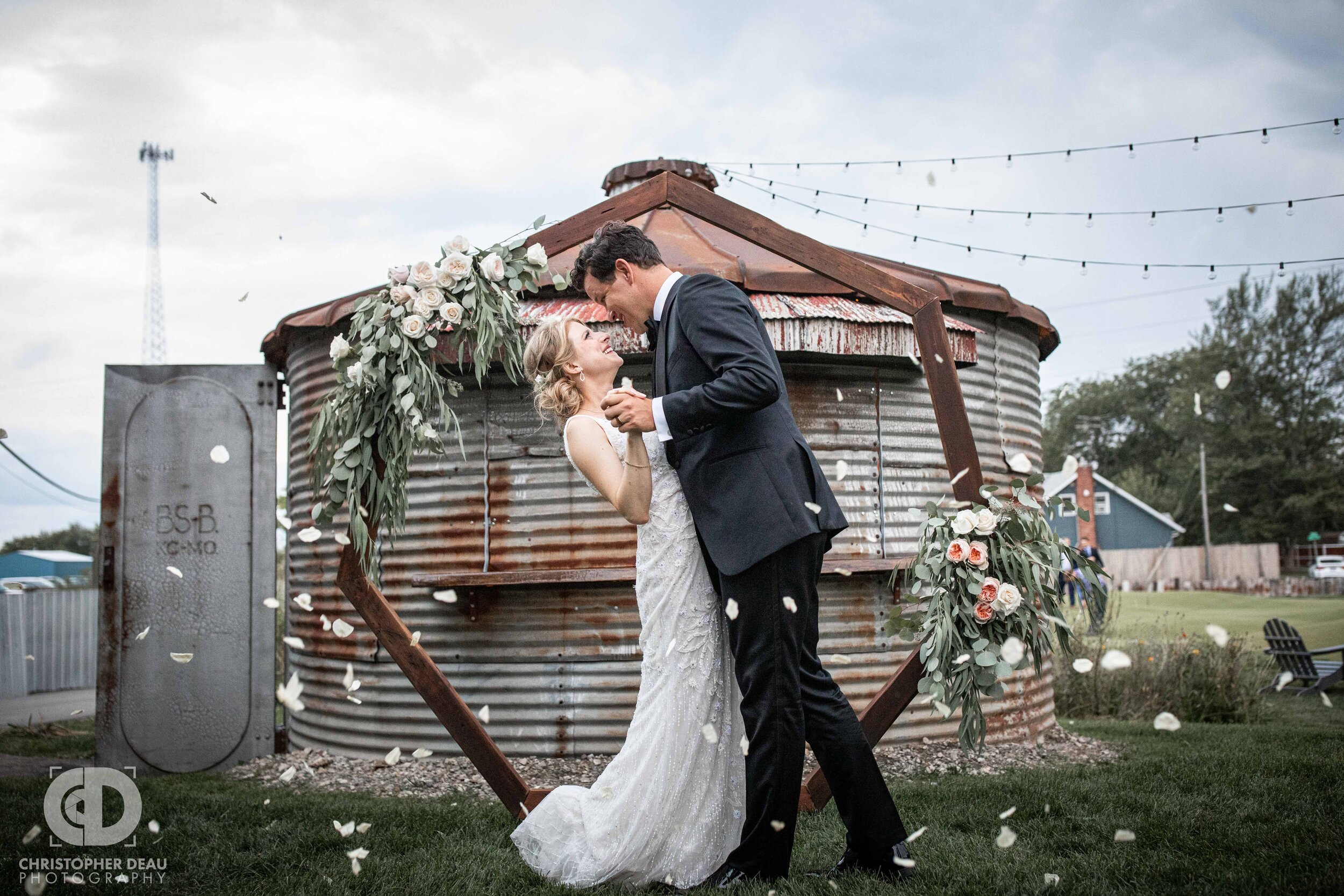  bride and groom first kiss with flower pedals tossed at journeyman distillery  