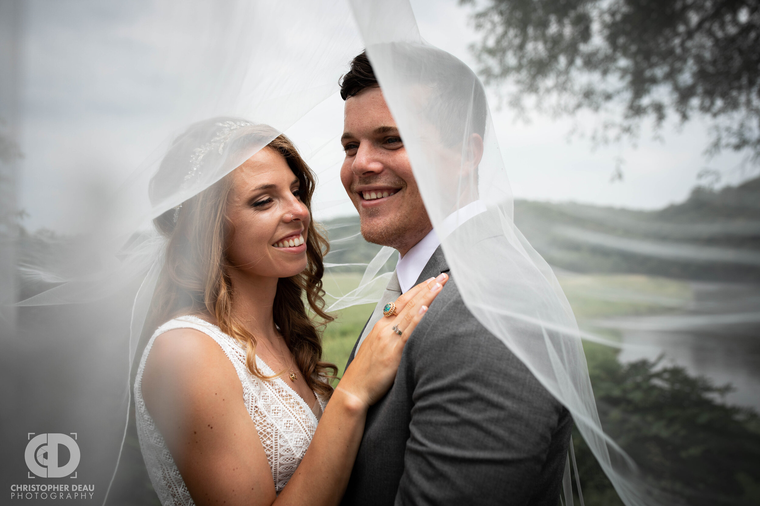  the bride’s veil is draped over the groom as they hold each other close 