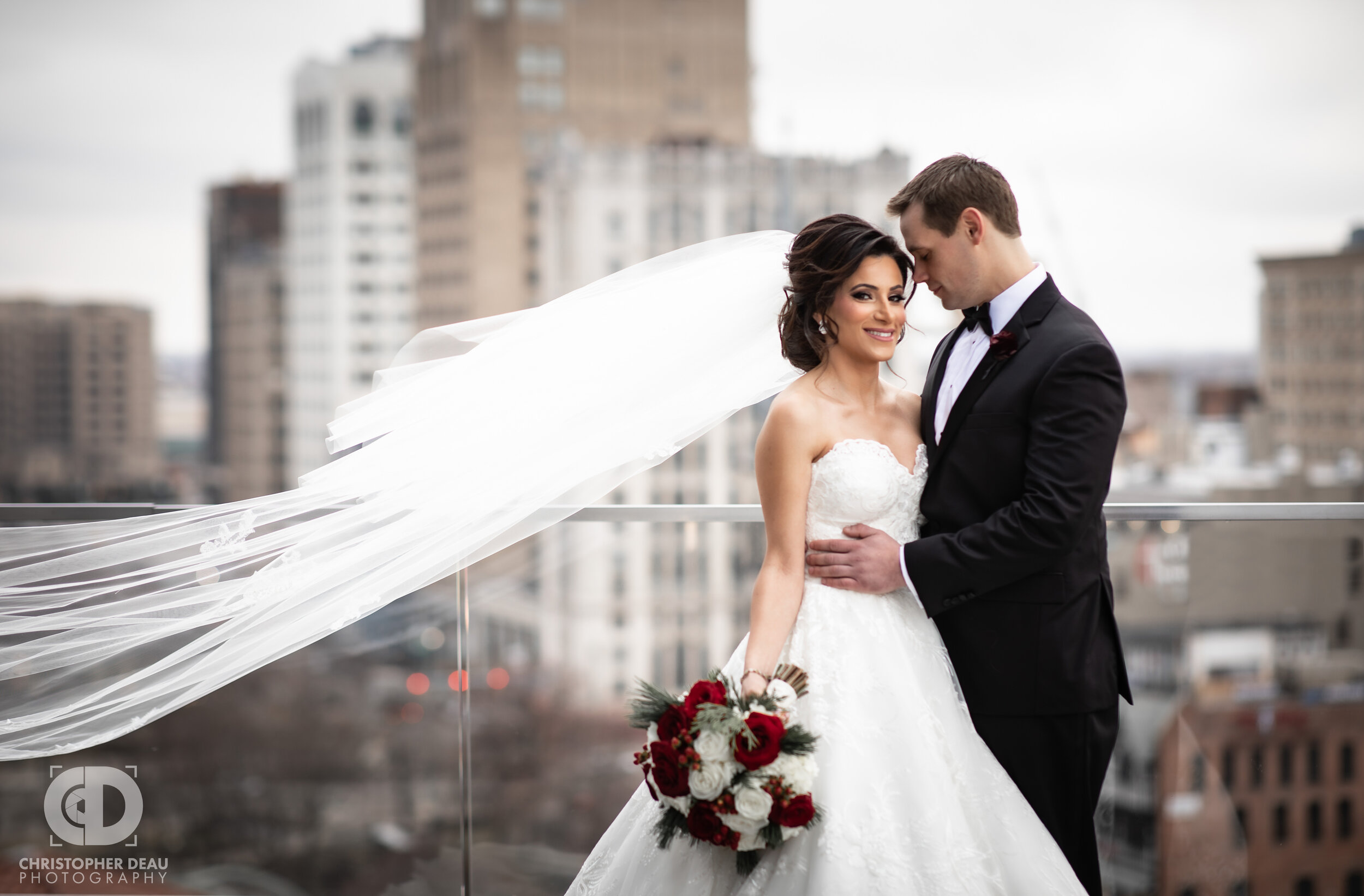  The bride’s veil flows in the wind on the rooftop of the Detroit Athletic Club as they look over the city 