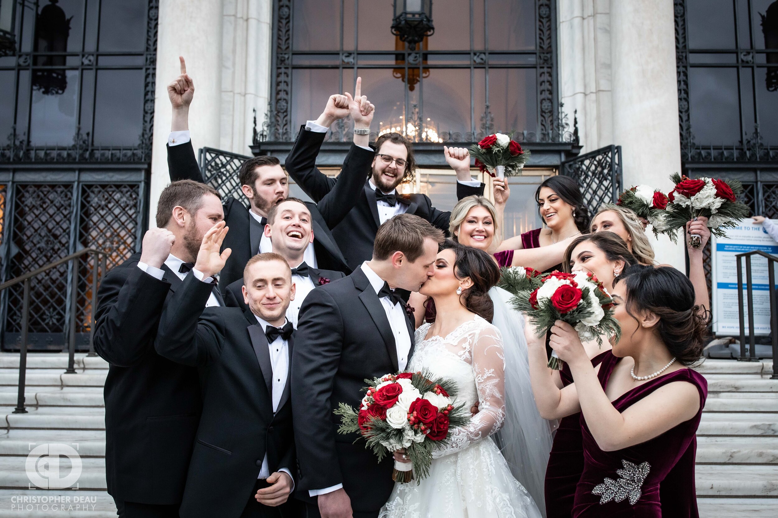  Entire wedding party cheers as the bride and groom kiss on the steps of the Detroit Institute of Arts 