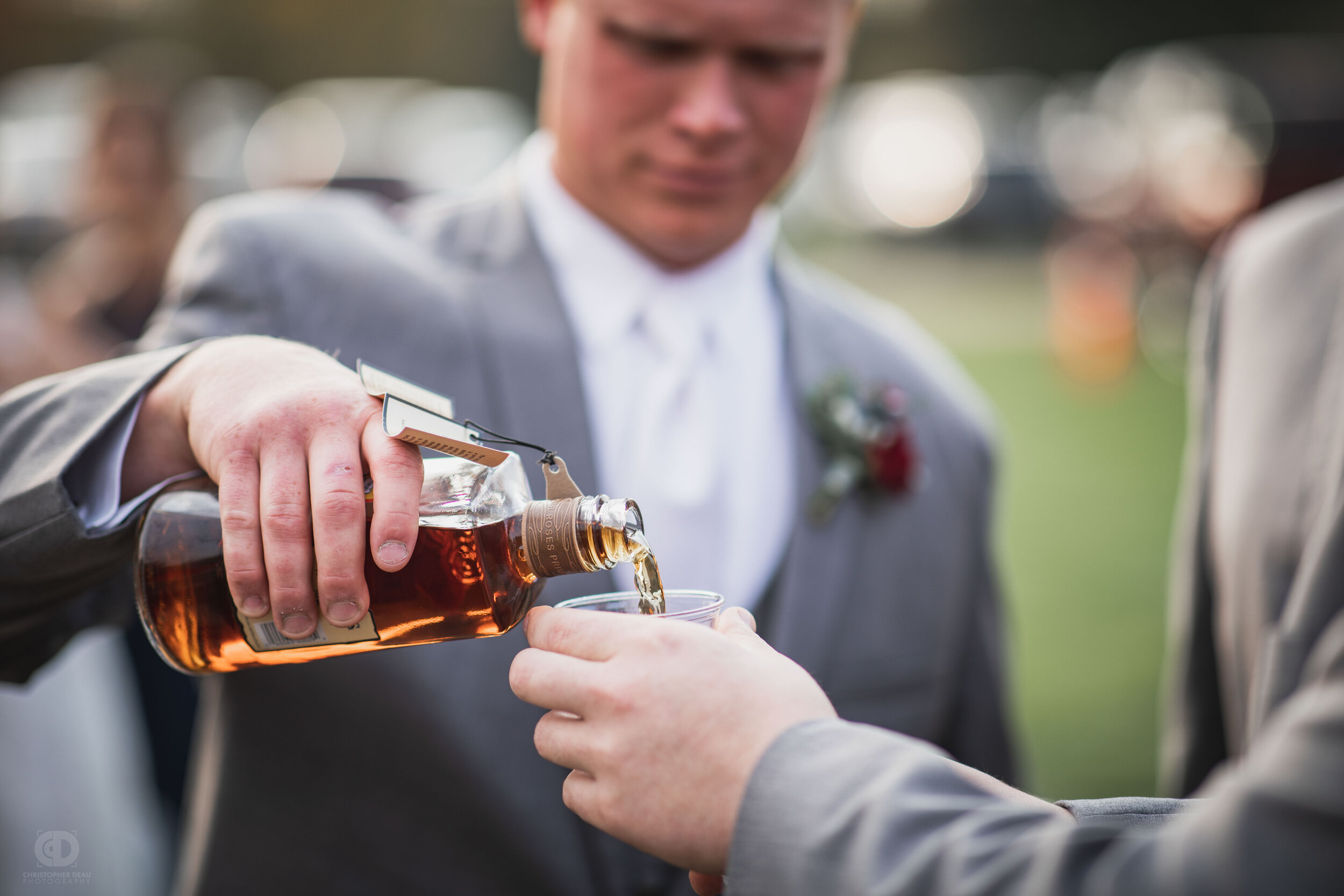  groom pours celebratory bourbon after the wedding ceremony 