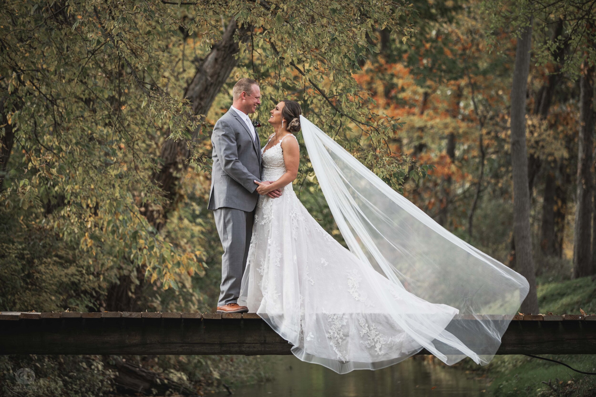  bride and groom on a bridge over a stream with fall colors 