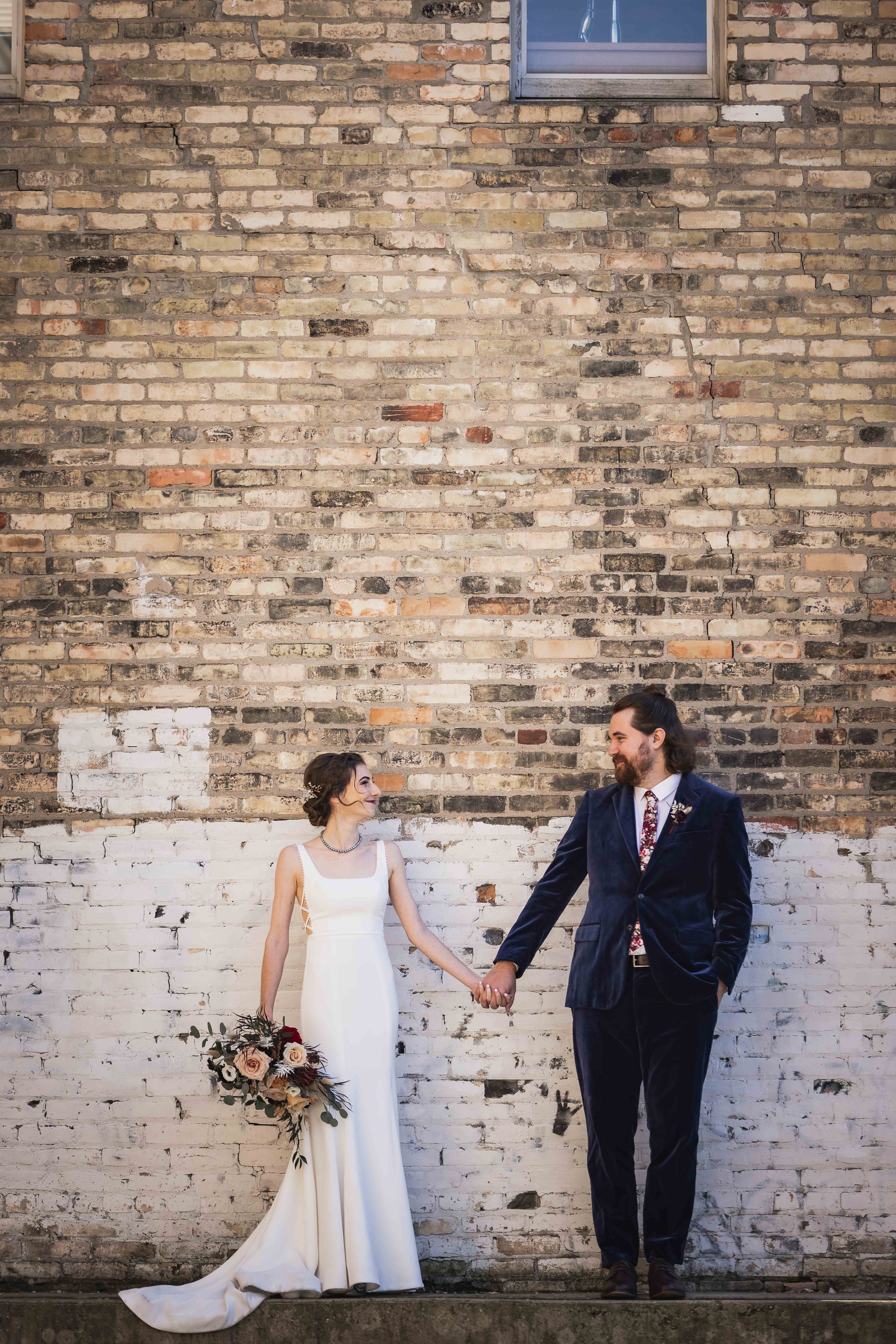  bride and groom portrait in front of brick wall 