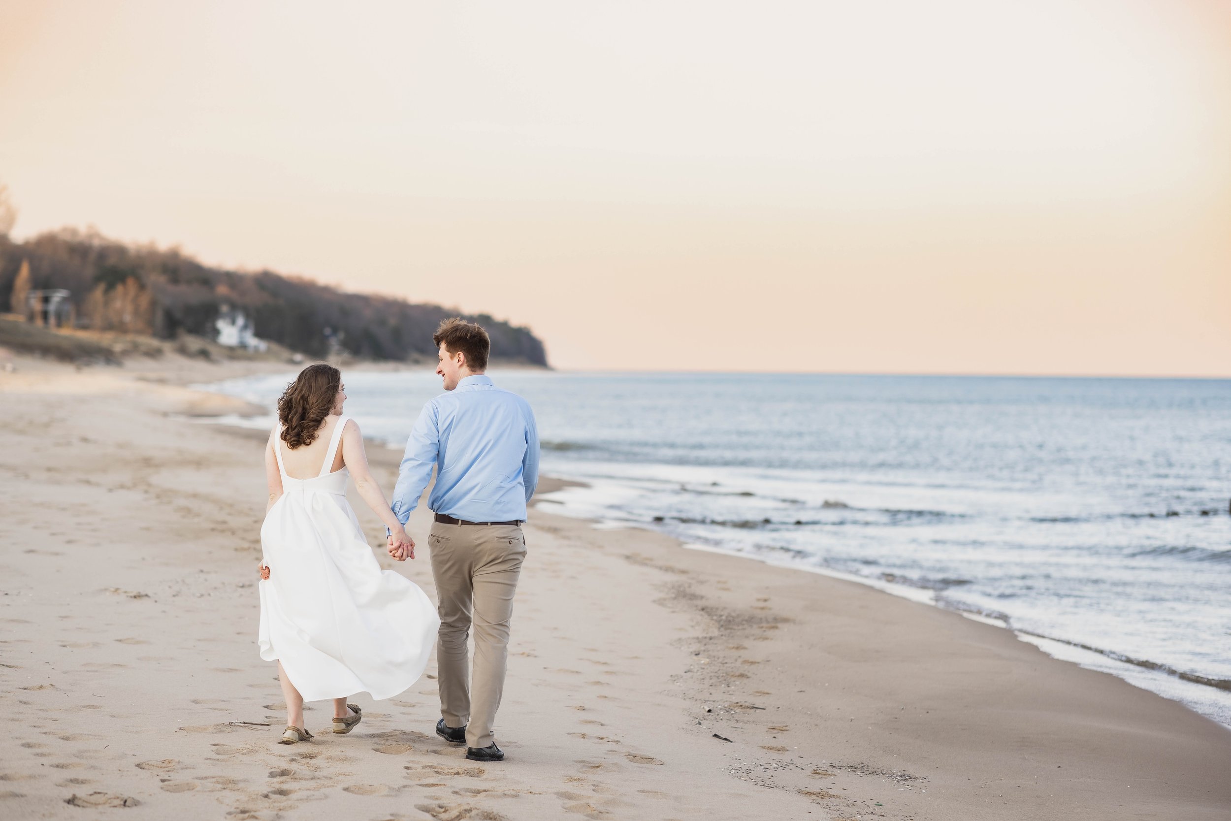  Couple walking away holding hands with a sunrise over lake michigan 