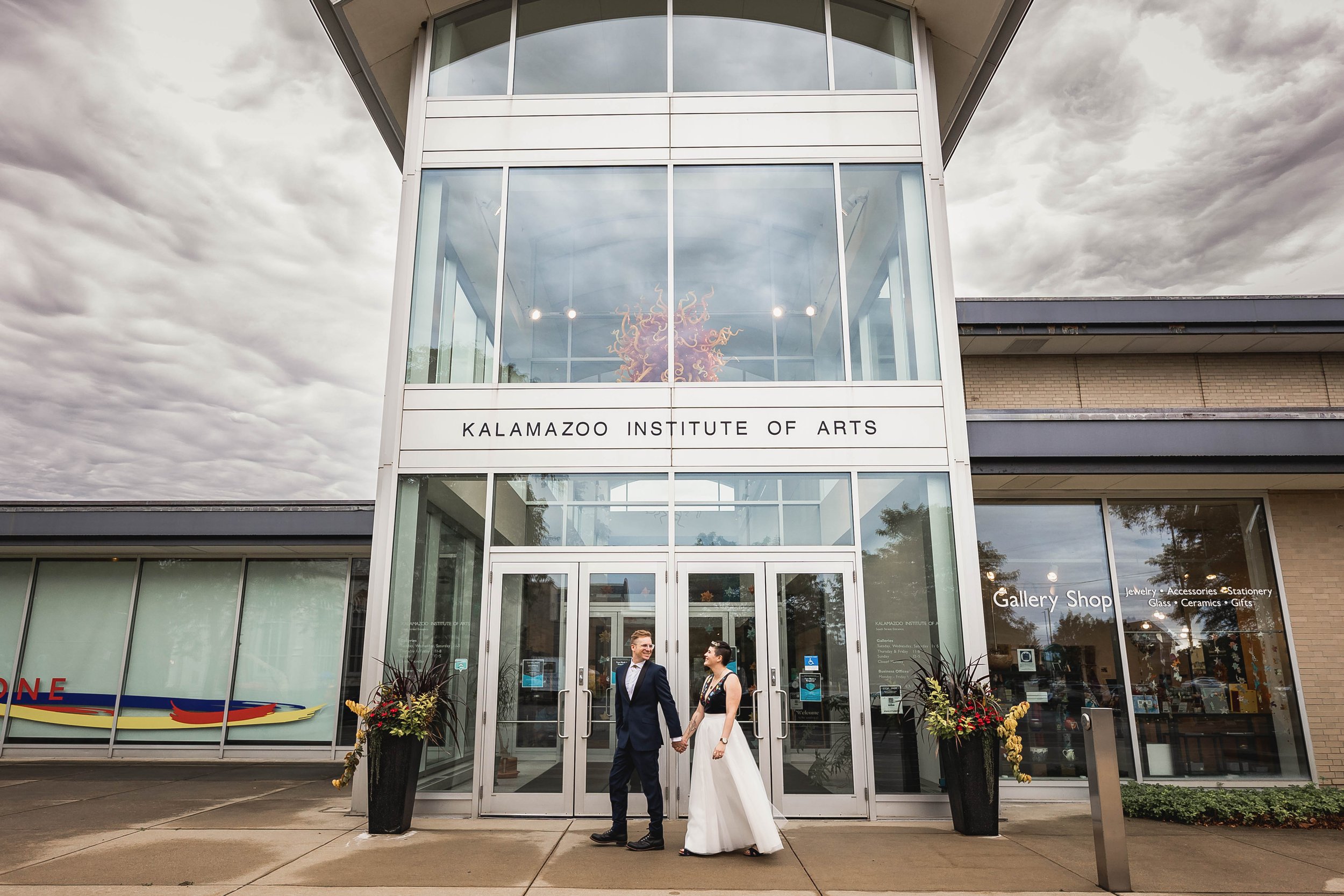  wide angle image of bride and groom walking in front of the Kalamazoo Institute of Arts  