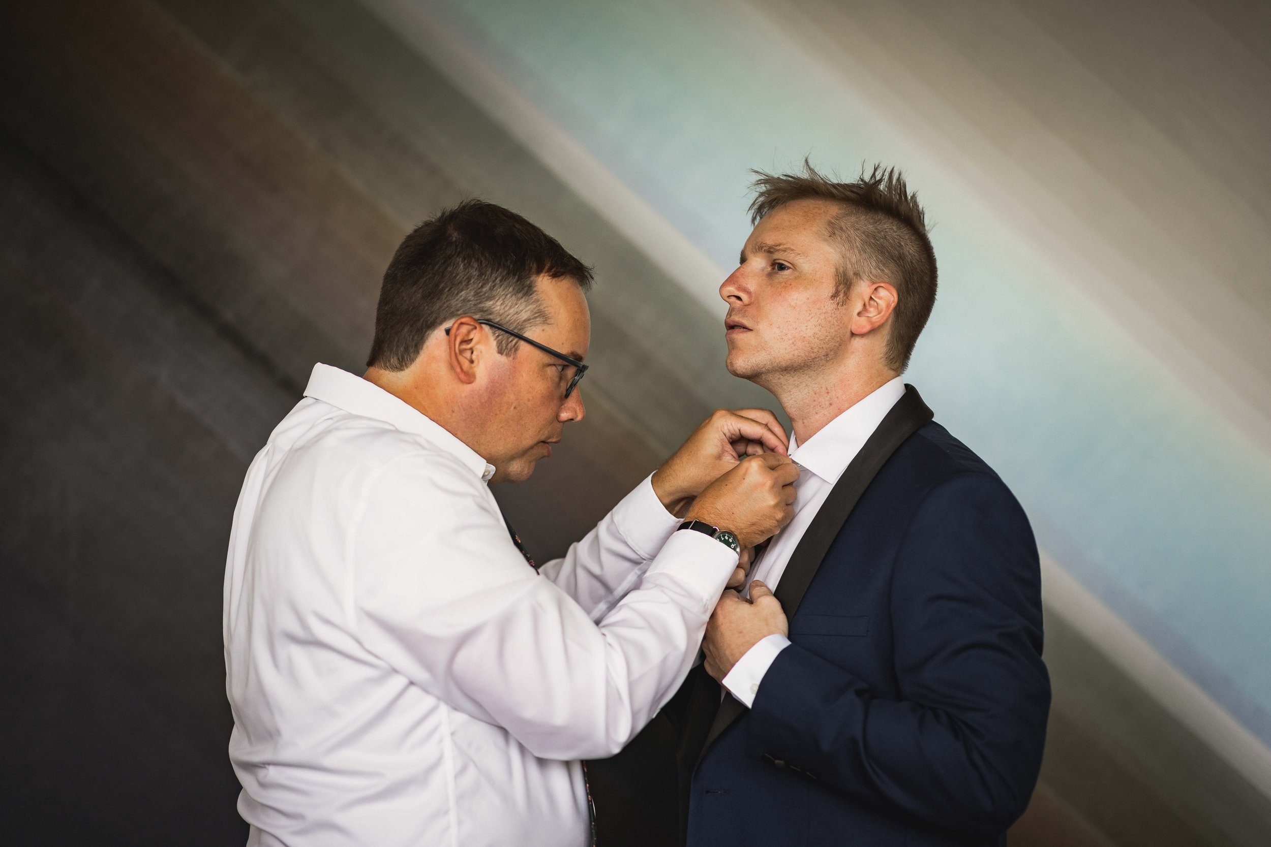  groom getting help with his tie 