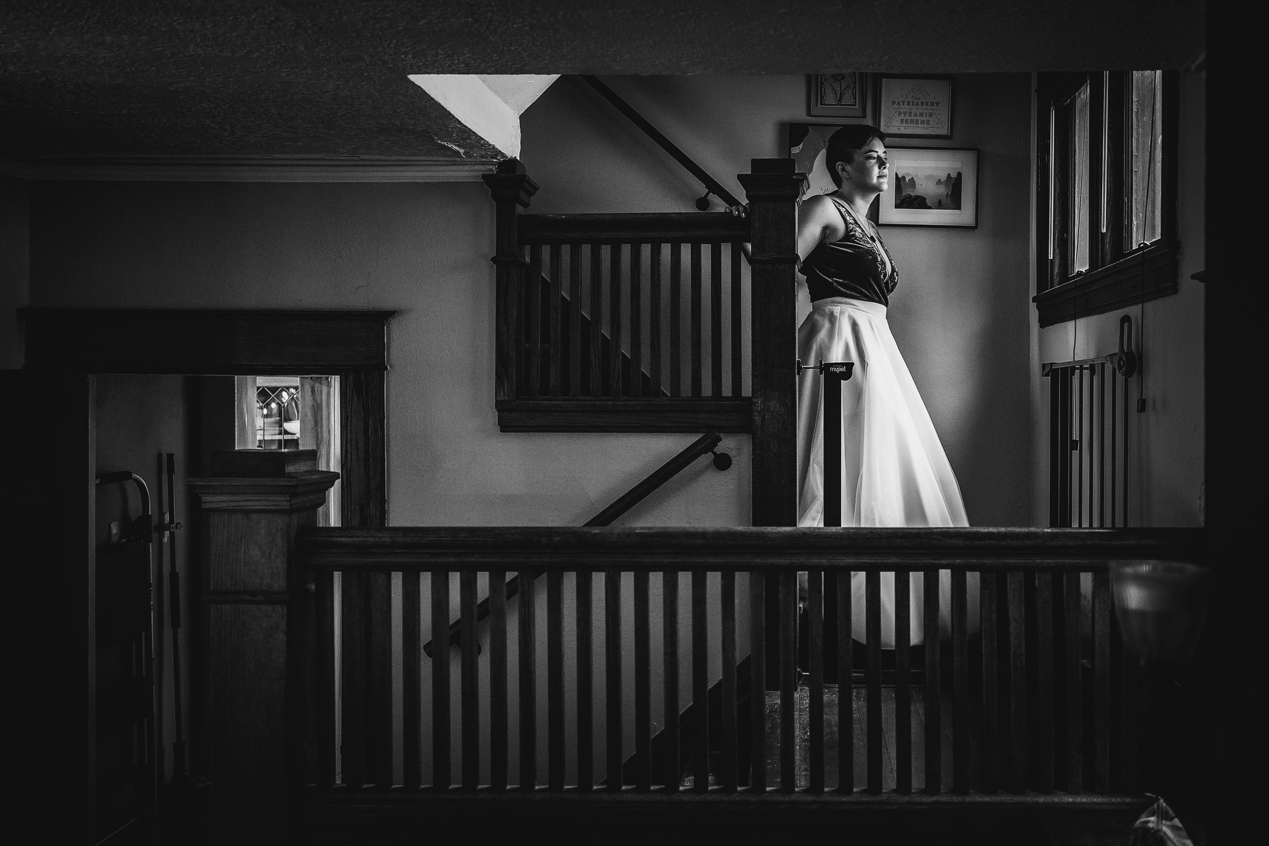  black and white image of bride walking down stairs in old house 