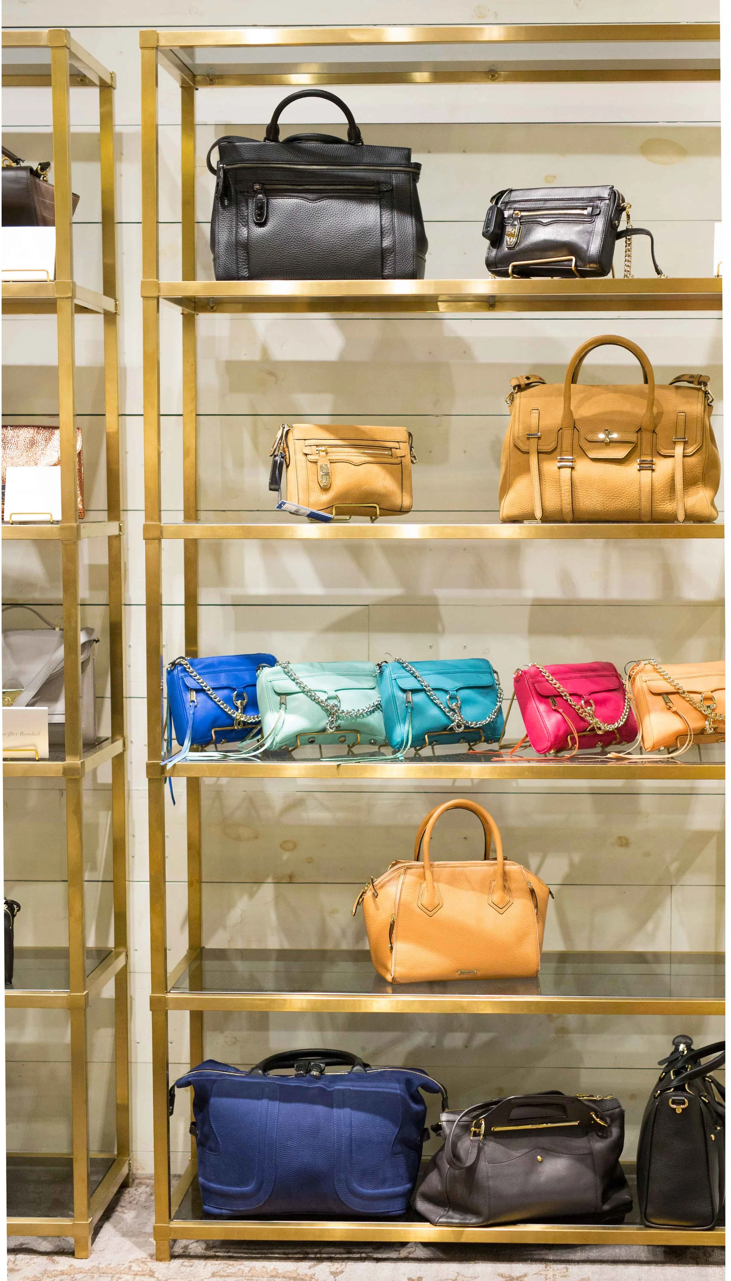 Custom brass bookshelves compliment the clothing racks on the opposite side of the store.