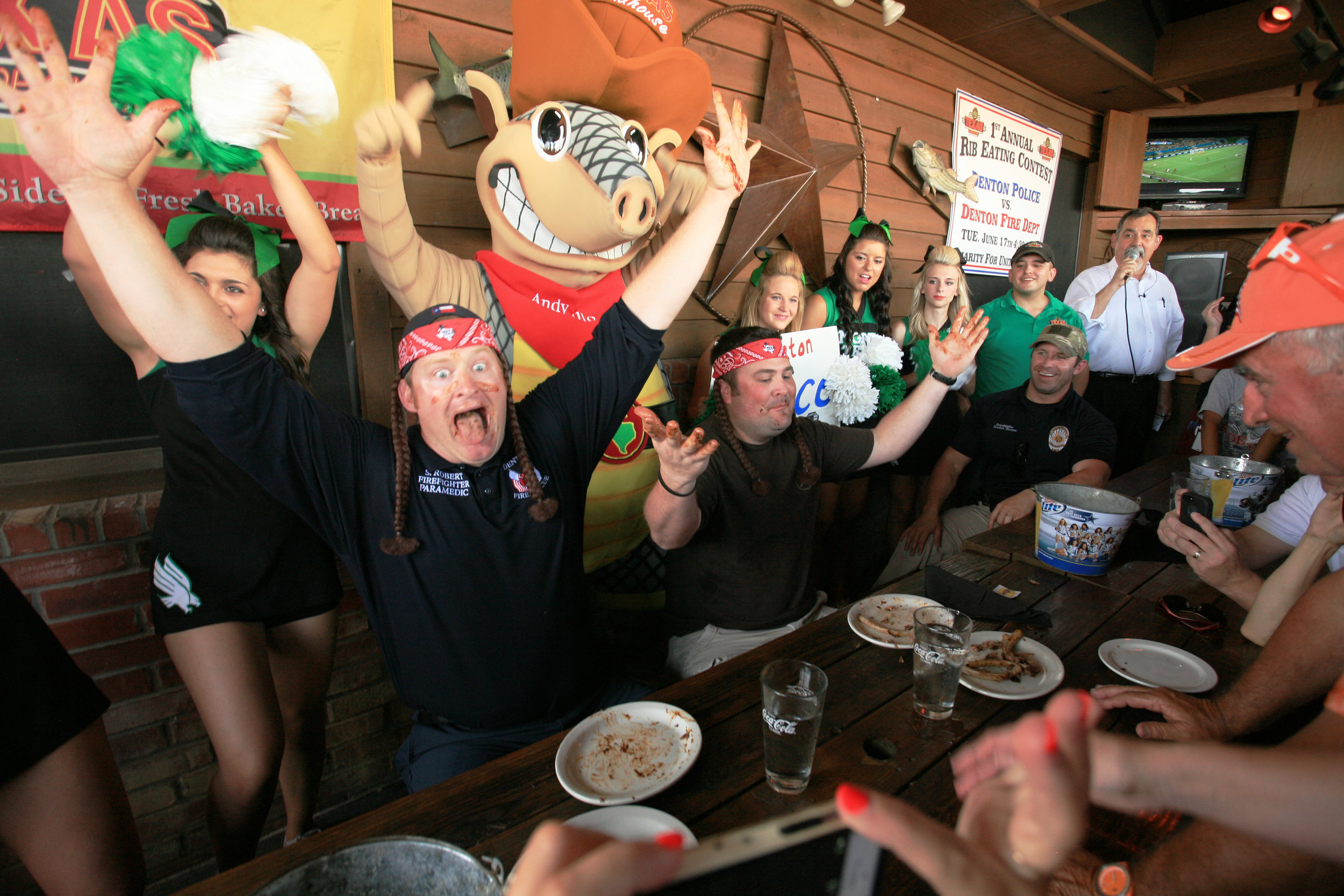 After a tie between the two teams, firefighter/paramedic Shane Robert shows his empty mouth to the judges and raises his arms in victory to defeat officer Cory McConnell in the first annual Firefighters versus Police rib eating contest at Texas Road