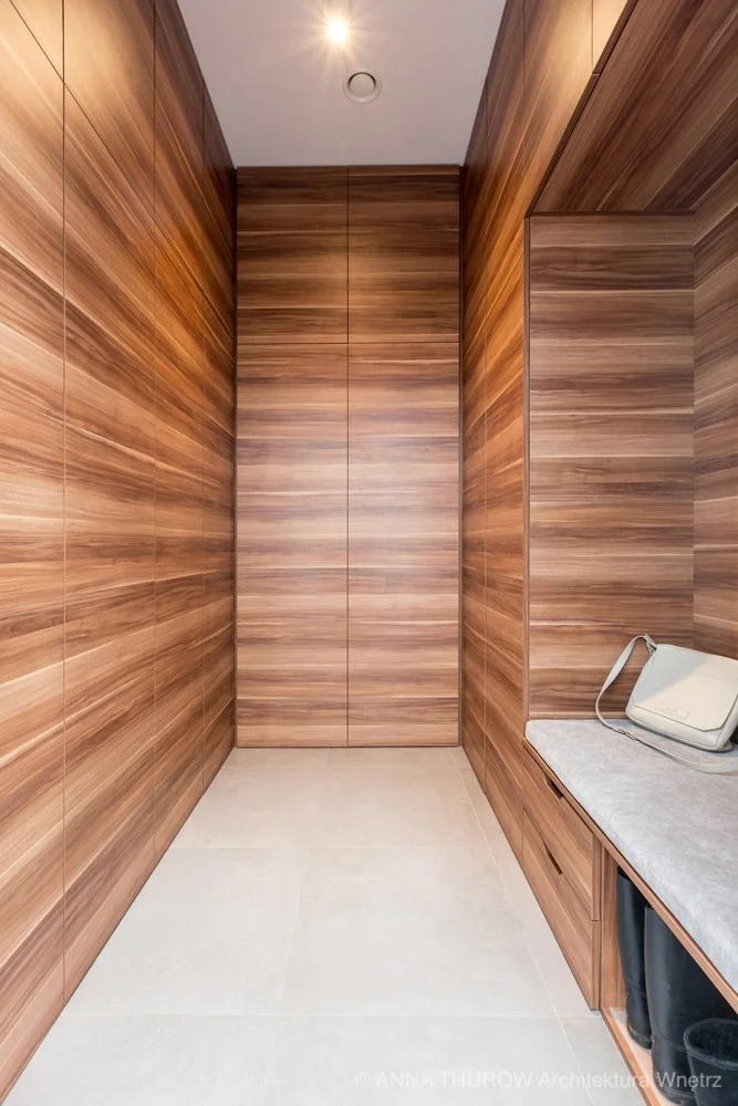 Drewniana garderoba wykonana w fornirze w nowoczesnym domu jednorodzinnym pod Szczecinem | kompleksowy projekt ANNA THUROW Architektura i wnętrza