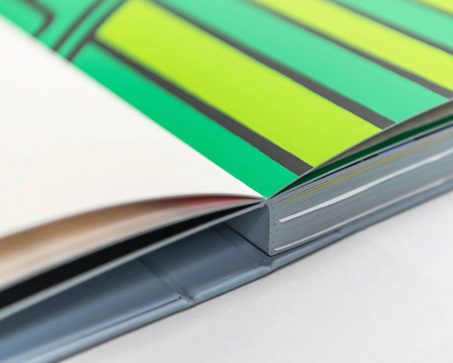 Close-up of a book with colorful, striped graphics on the printed pages and a silver cover, resting on a white surface.