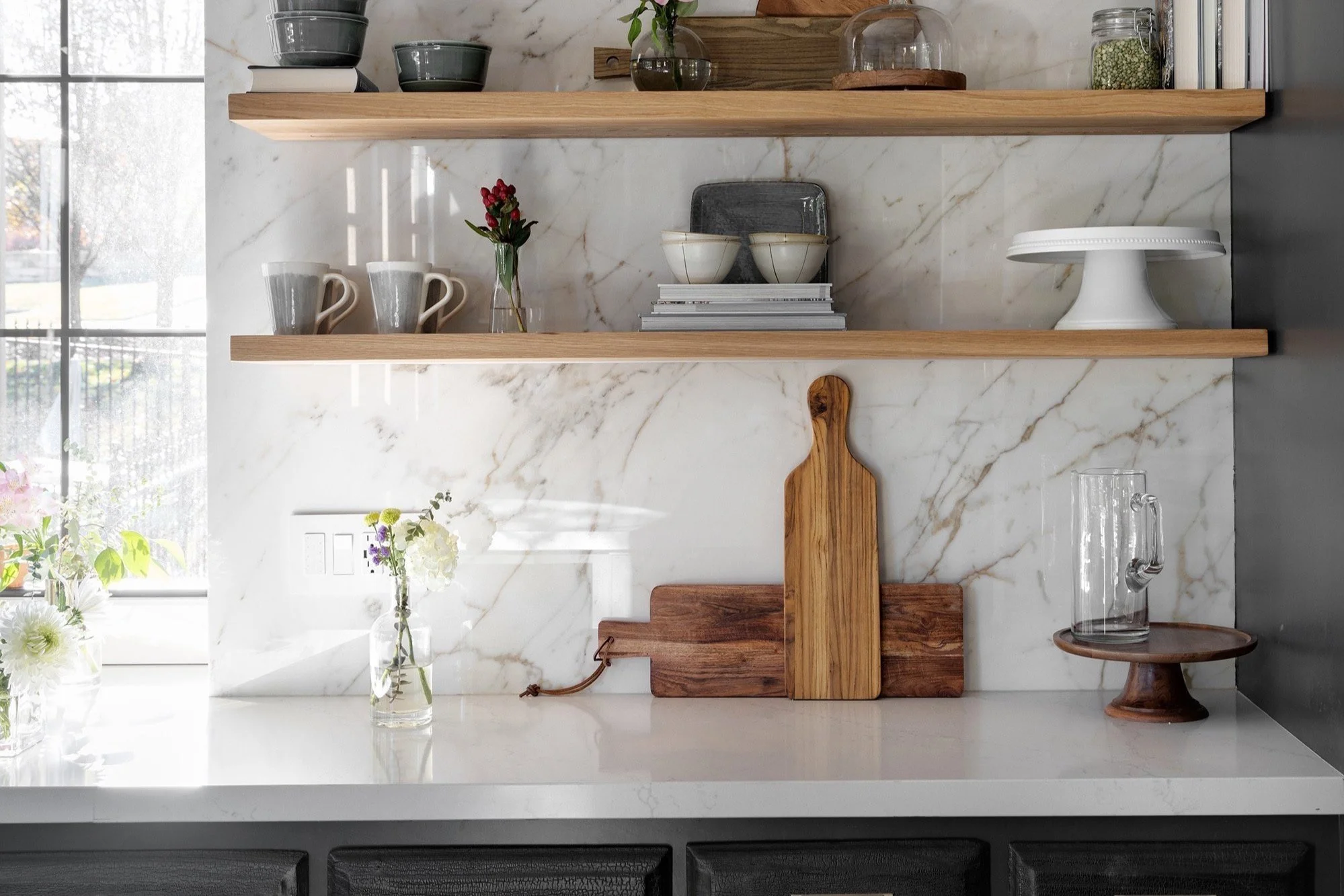 Marble-style porcelain kitchen wall with floating wood shelves.