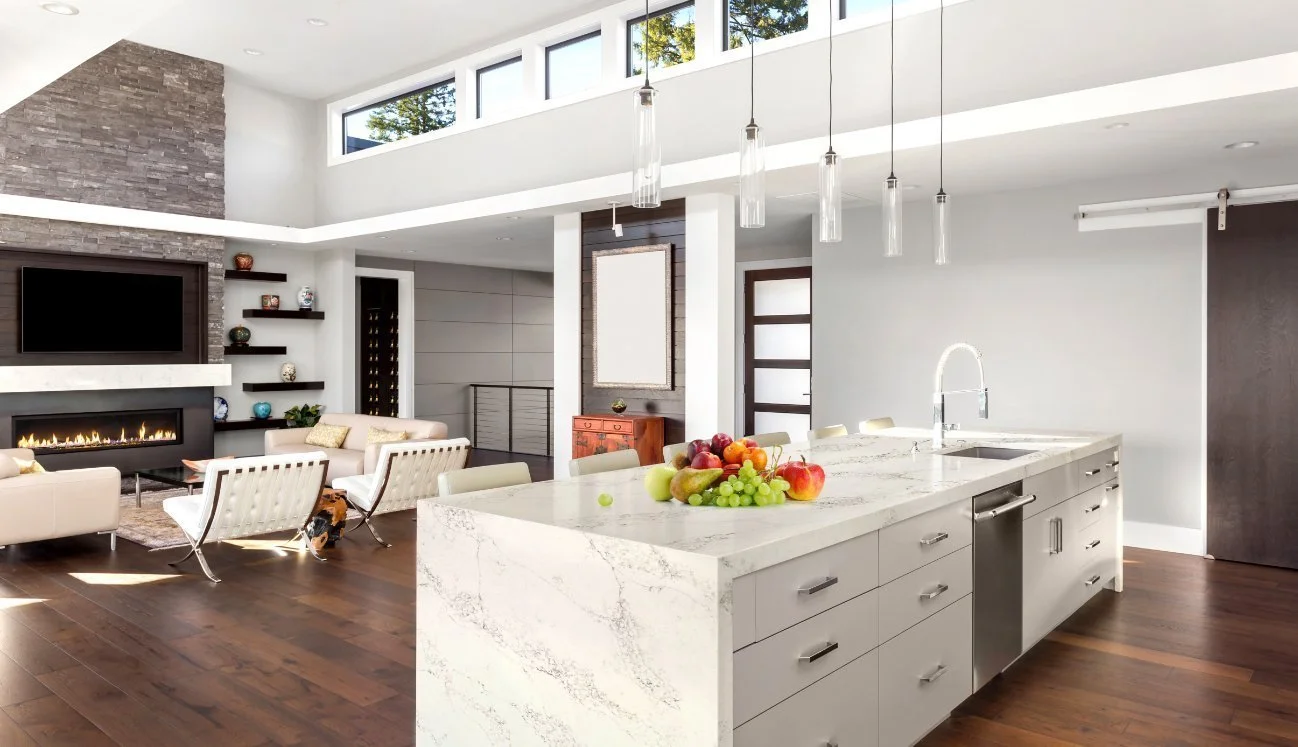 Statuario Gold quartz island with white cabinets in modern open house.