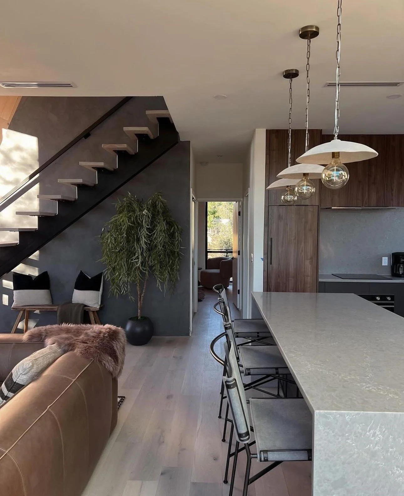 Dappled grey and white Aurora quartz island and backsplash are set in an open home concept with wood cabinets and leather couch.