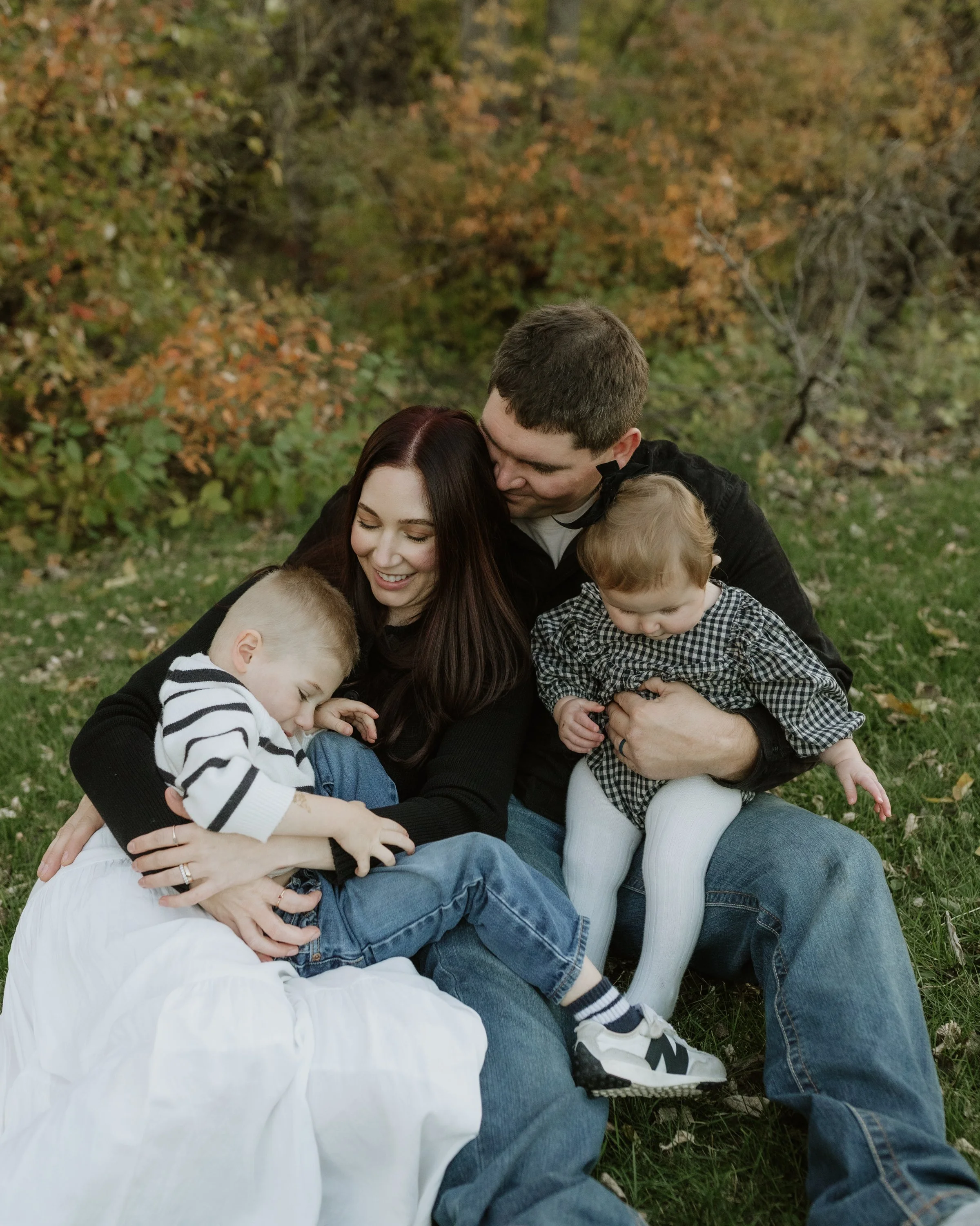family cuddling in the fall leaves for photos