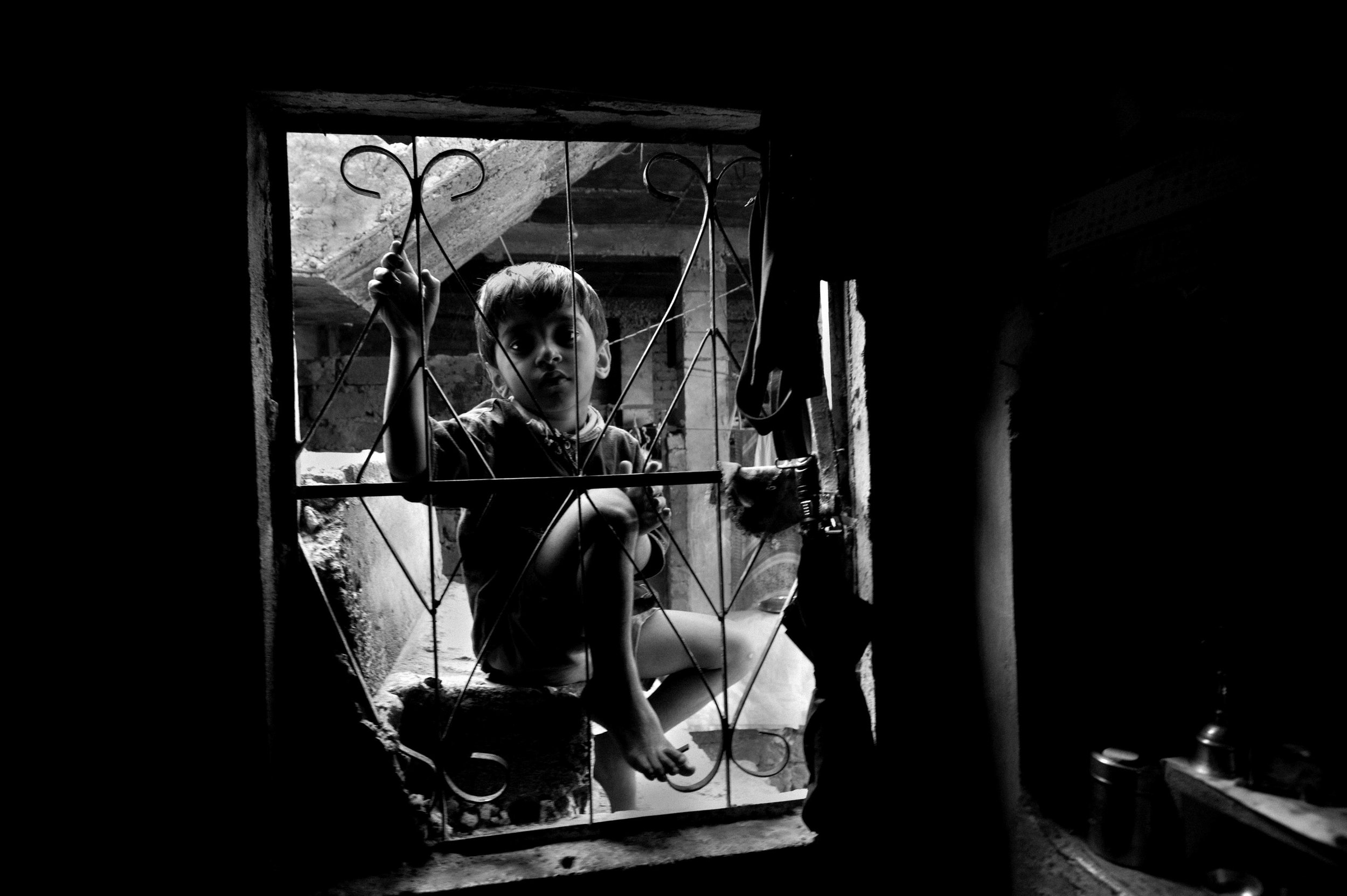  A boy looks into the window of a home near the site of the Union Carbide plant behind him in the city of Bhopal in the state Madhya Pradesh, India. 