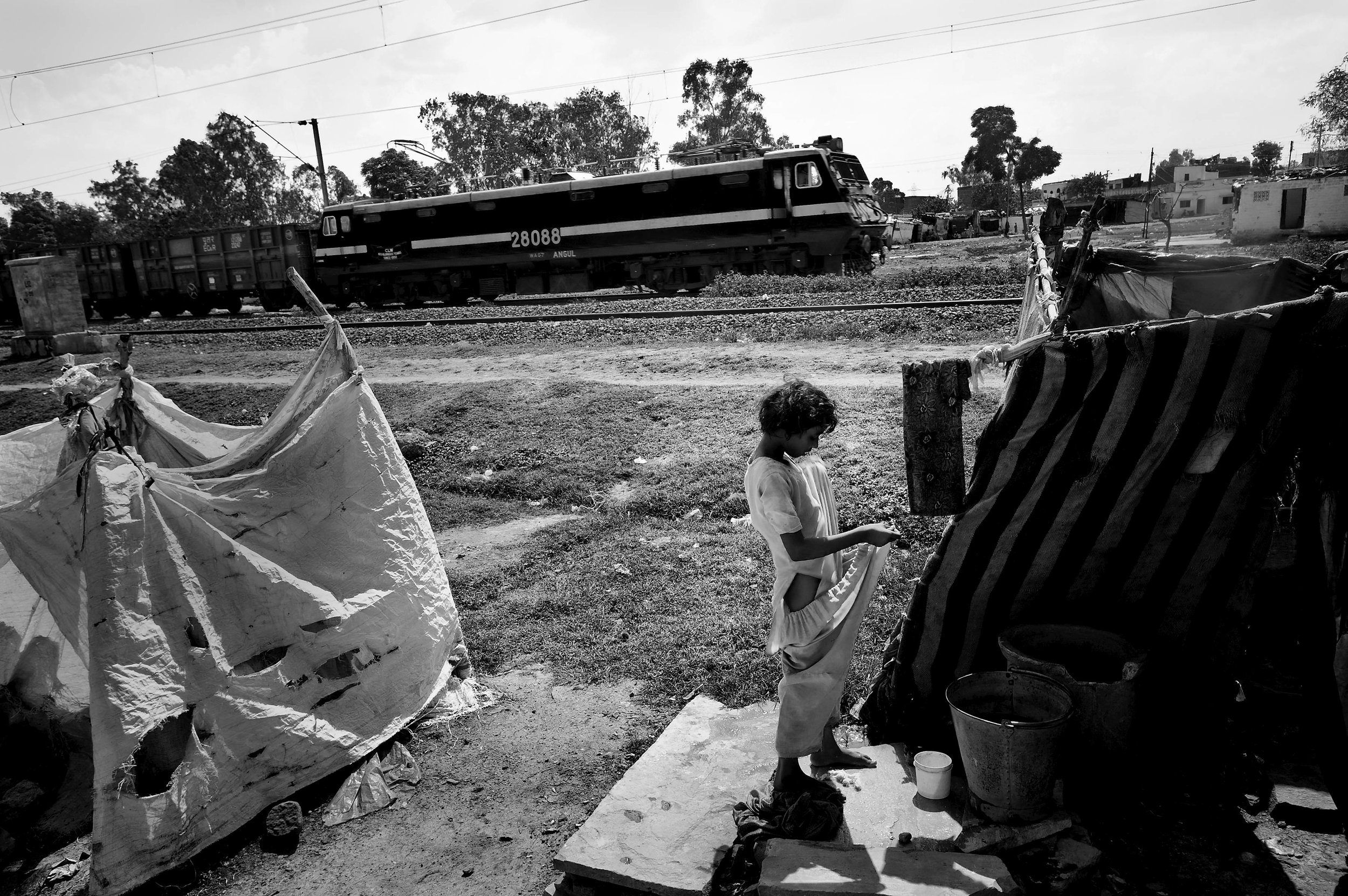  A girl dresses as a train makes its way in front of the shack she lives on the site of the Union Carbide plant behind him in the city of Bhopal in the state Madhya Pradesh, India. 