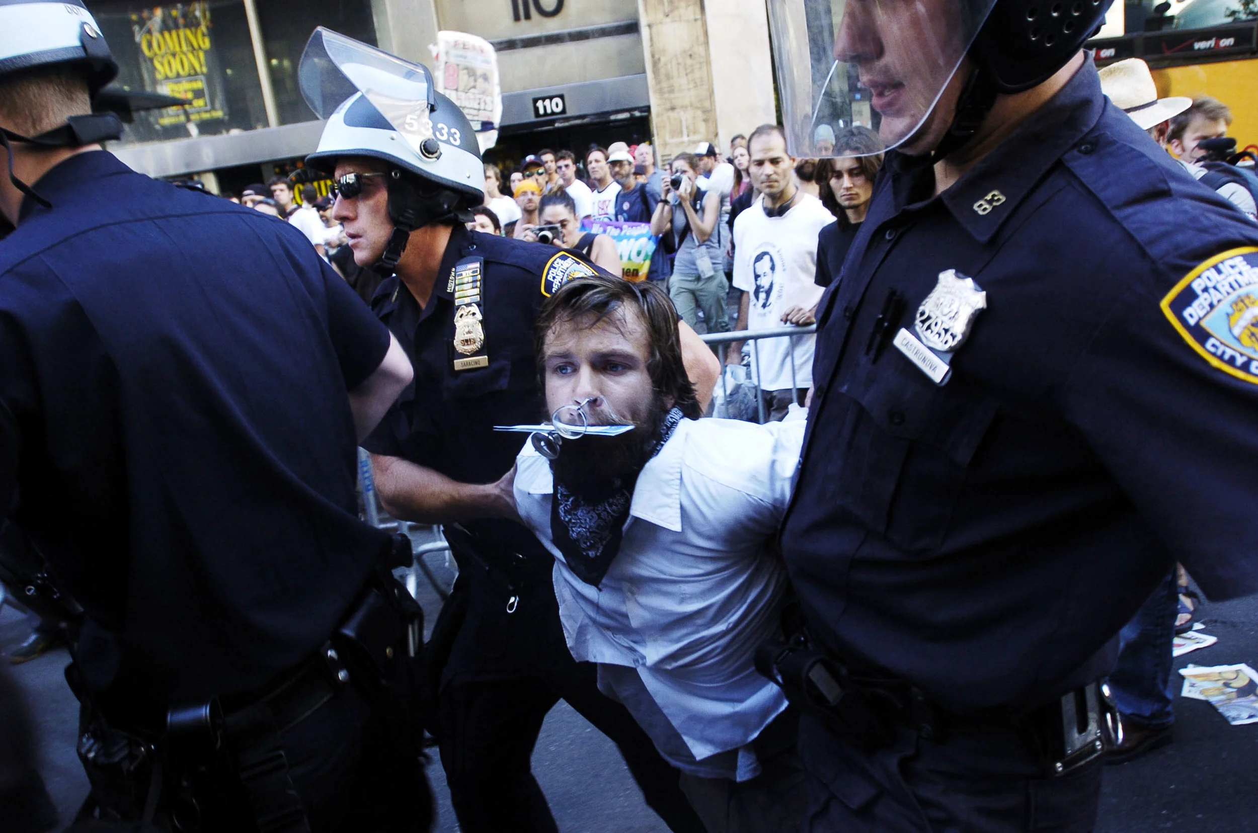 Law enforcement officers arrest demonstrators after a papier-mâché dragon was set on fire by anarchists on Seventh Avenue near Madison Square Garden August 29, 2004, in New York City. Police arrested dozens as thousands of protesters marched to the site of the Republican National Convention.