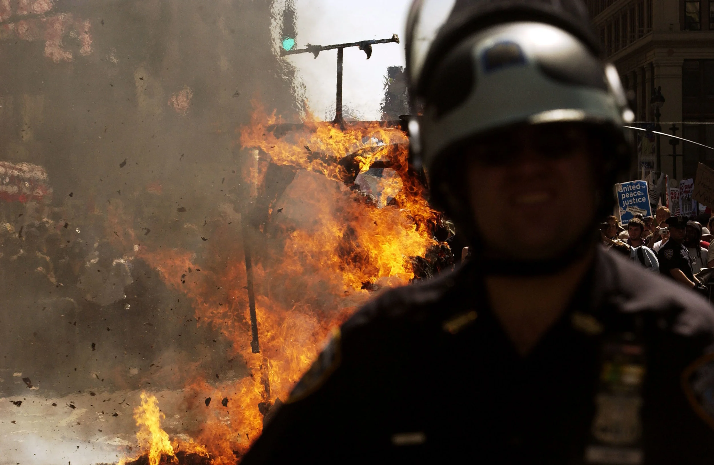 Police watch as a papier-mâché dragon set on fire by anarchists burns on Seventh Avenue near Madison Square Garden in New York City. Police arrested dozens as thousands of protesters marched to the site of the Republican National Convention.