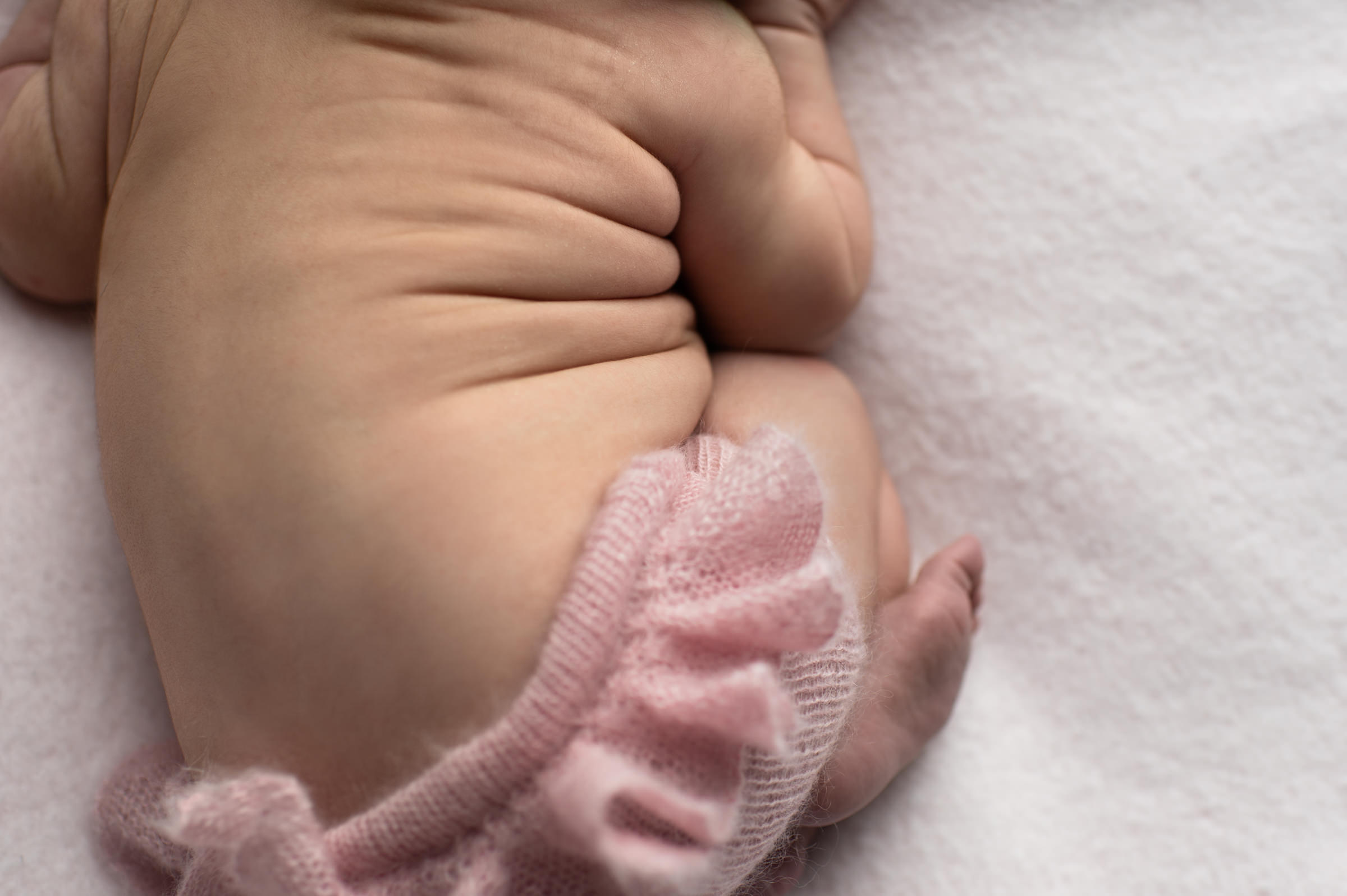 Tummy wrinkles of a newborn baby girl on pink