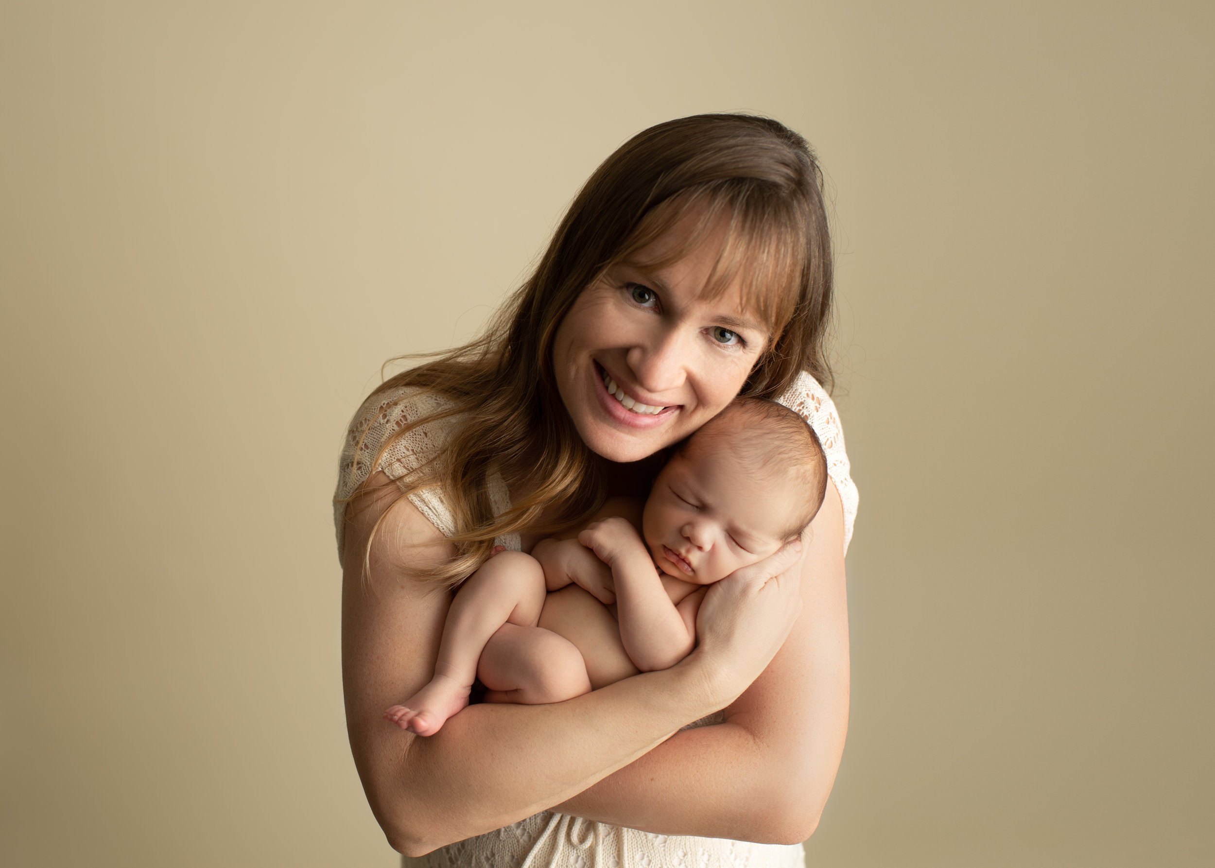 proud mom smiling at camera with newborn boy