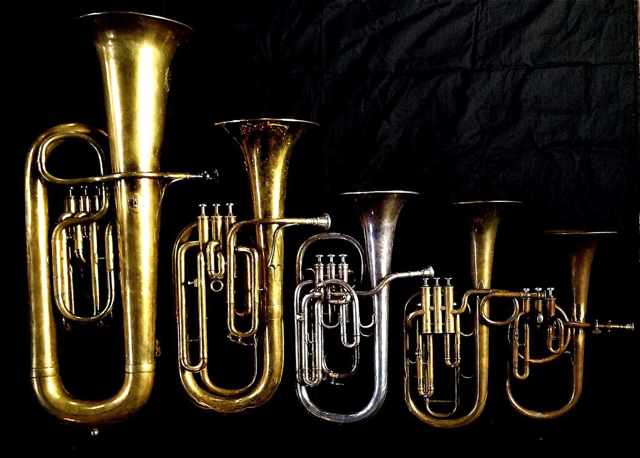 Left to Right: Contrabass saxhorn in E-flat by E. Daniel (7167, Marseille, c. 1850), Baritone saxhorn in B-flat by Couesnon (44139, 94 Rue D’angouleme Exposition Universelle De Paris, 1900) , Tenor saxhorn in E flat by Boosey & Co (47317, 295 Regent Street, London, 1900). Tenor saxhorn in F/E flat/D by Antoine Courtois (Paris, c. 1855), sold by Arthur Chappell (London), Contralto saxhorn in B-flat by J. Grass (32 Rue des Ponts de Comines, Lille, est. 1868.