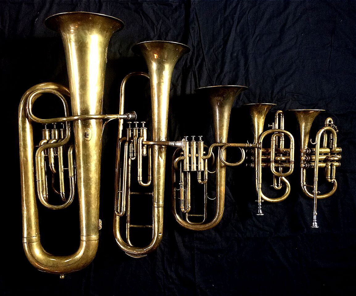 Left to Right: Contrabass saxhorn in E-flat by E. Daniel (7167, Marseille, c. 1850), Baritone saxhorn in C/B flat by Couturier (Lyon, c. 1865), Tenor saxhorn in F/E flat/D by Antoine Courtois (Paris, c. 1855), sold by Arthur Chappell (London), Cornet in B-flat/A by F. Besson (44292, 96 Rue D’angouleme, Paris c. 1892) , Cornet in E-flat by Couesnon (94 Rue D’angouleme Exposition Universelle De Paris 1900).