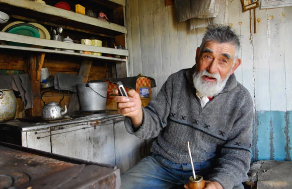 Faustino sipping yerba mate in his home made from an upturned boat.