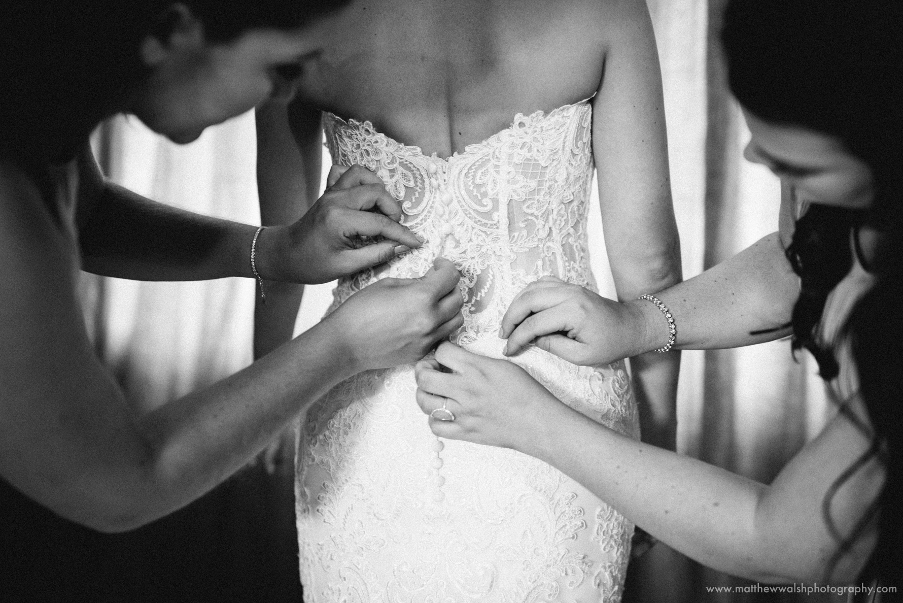 The bridesmaids help with the tradition of buttoning up the brides dress