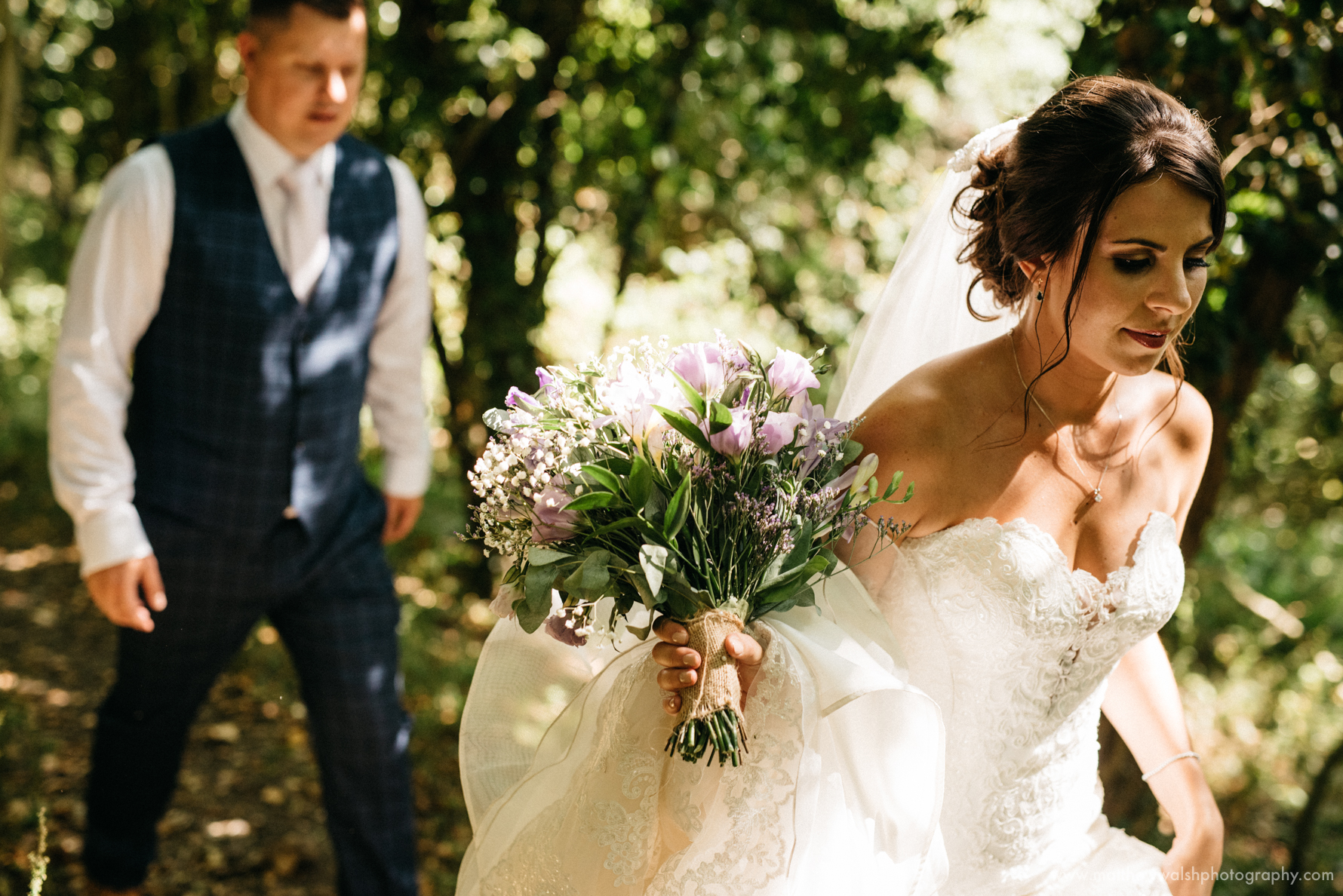 A stunning artistic photograph as the bride and groom walk through the amazing forest backdrop