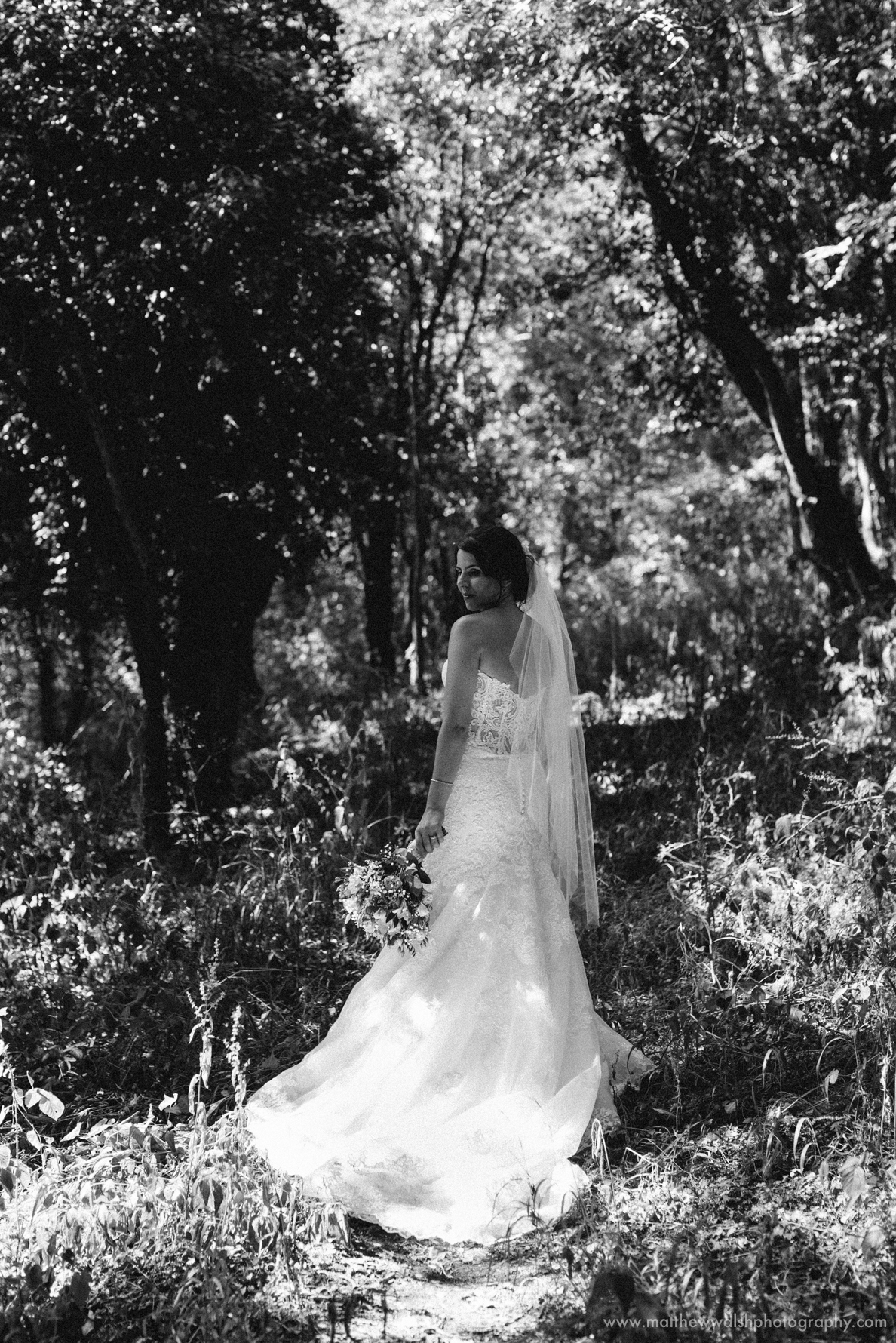 The back of the brides dress as she is framed by a natural backdrop all in wonderful black and white photography